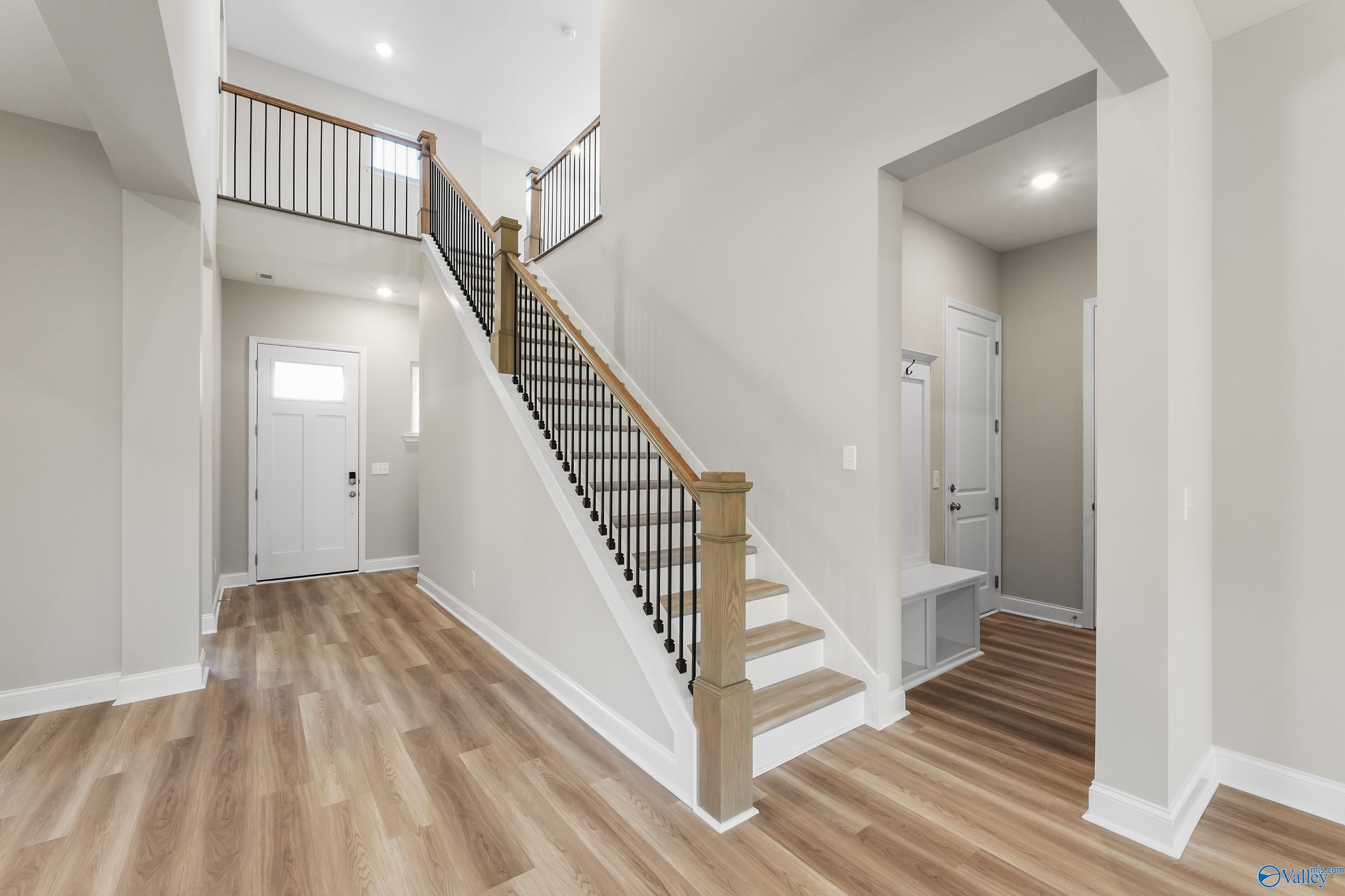 Grand two-story foyer with wrought iron staircase and hardwood floors in Evermore Homes The Haven, Owens Cross Roads, Alabama
