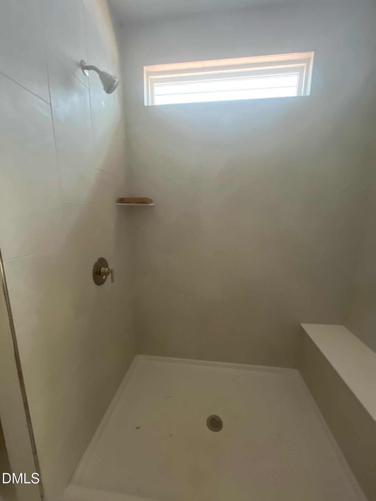 Modern walk-in shower with white tiles, built-in bench, rainfall head, and frosted window in The Ashport G primary bath, Wake Forest NC