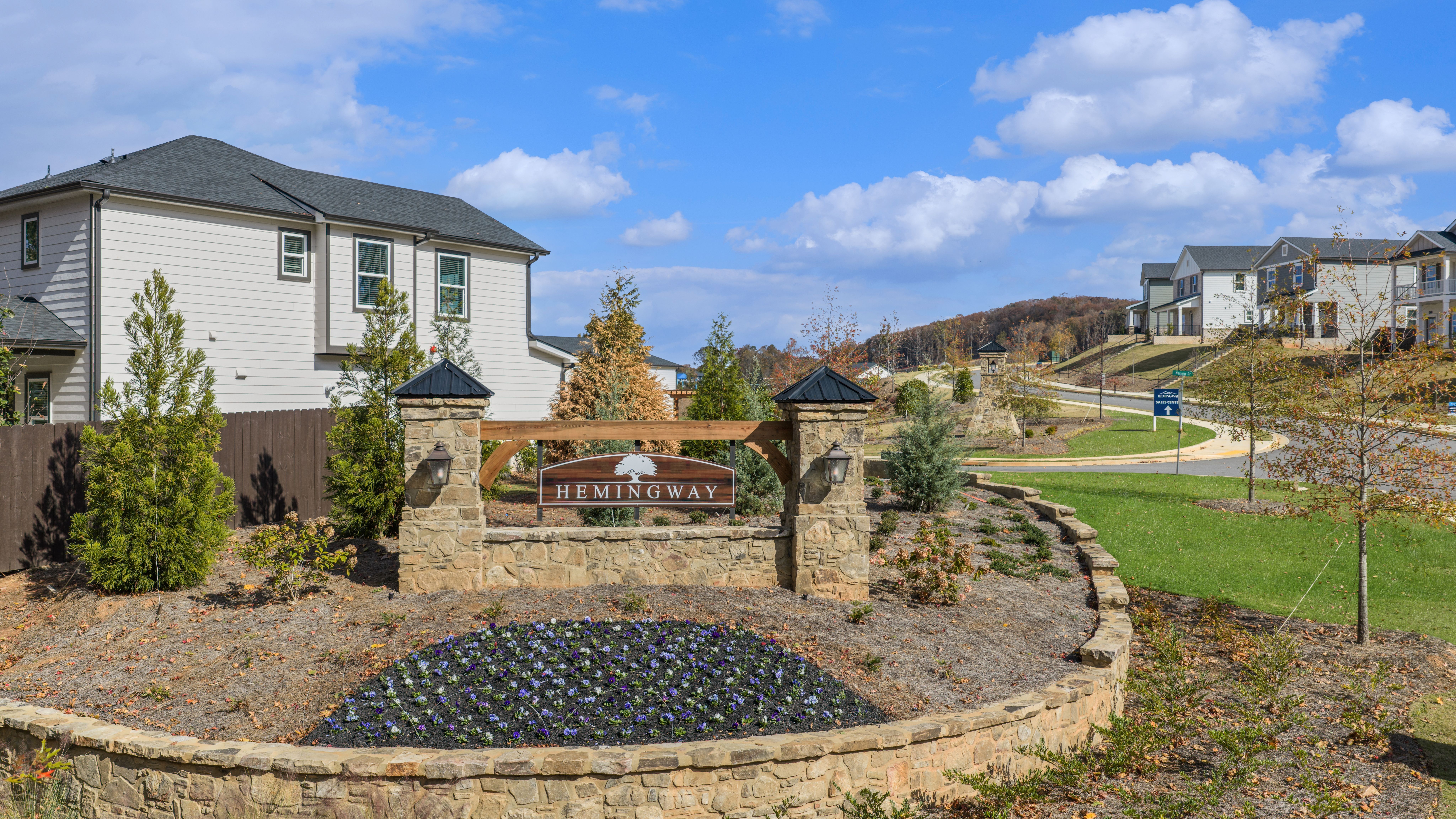 Hemingway community entrance in Cumming Georgia with stone pillars, welcome sign, landscaped gardens and modern homes