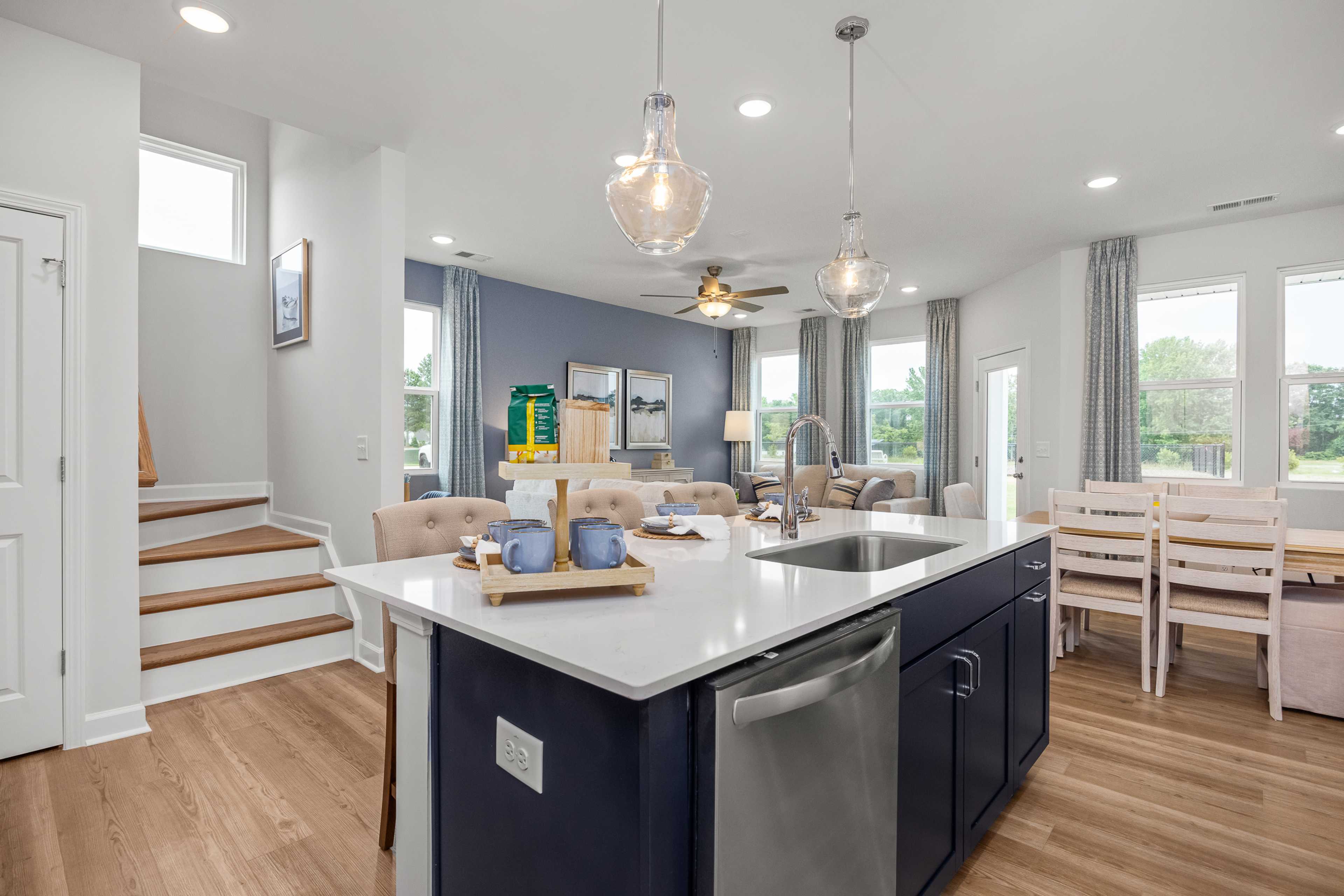 Open-concept kitchen and dining at Springvale in Fuquay-Varina NC with navy island, quartz counters, hardwood floors