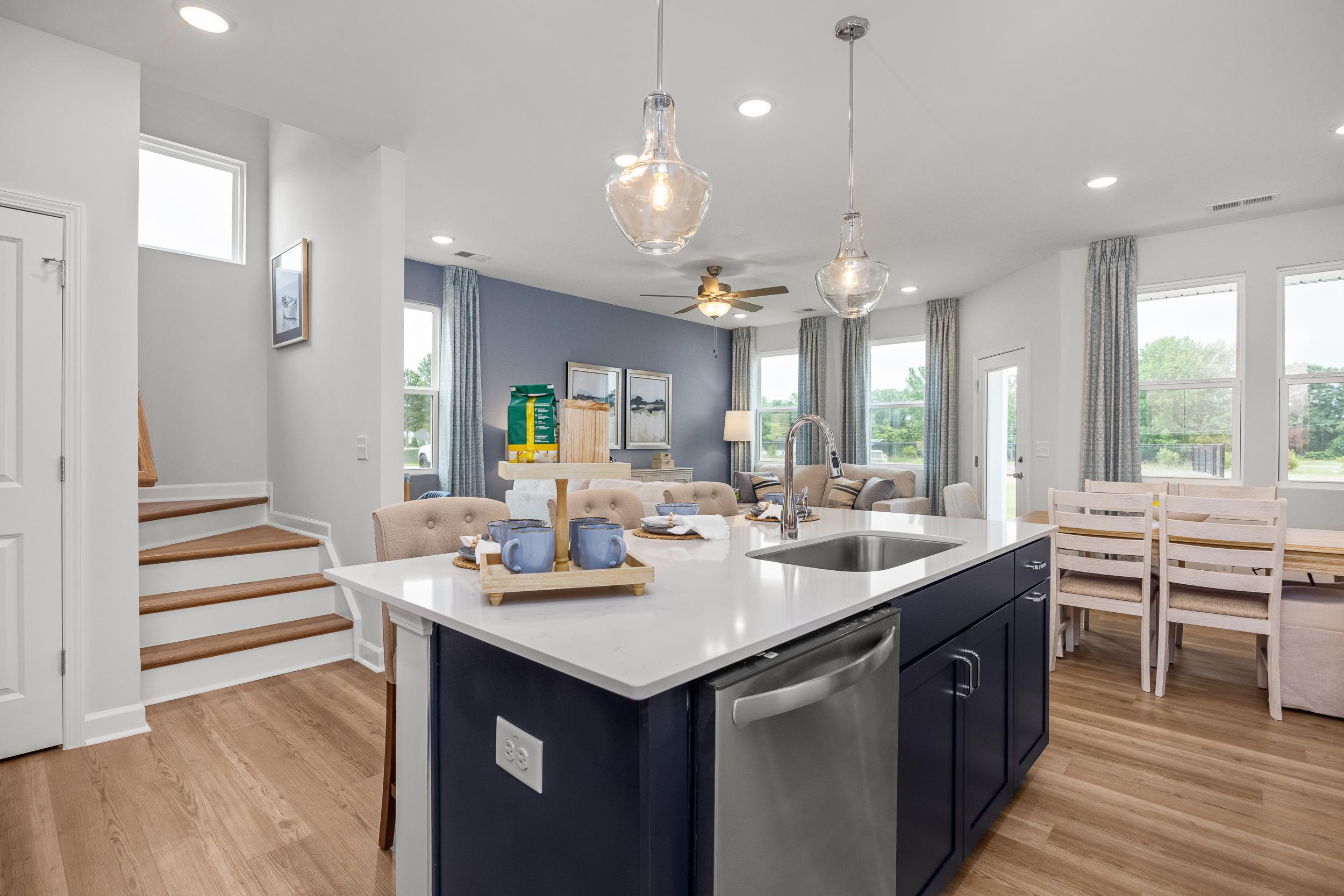 Open-concept kitchen and dining at Springvale in Fuquay-Varina NC with navy island, quartz counters, hardwood floors