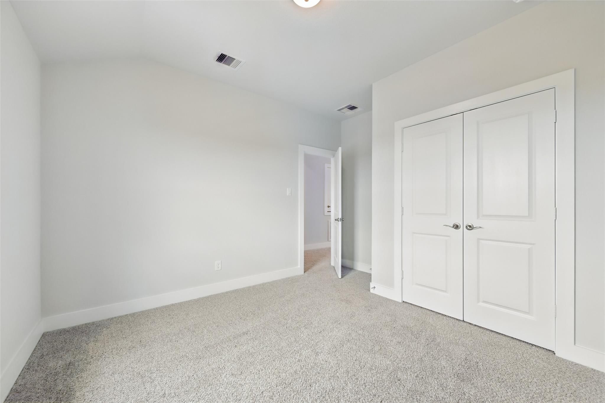 Spacious secondary bedroom with vaulted ceiling, beige carpet, and double closet doors in Davidson Homes The Philip A, Lago Mar, Texas City