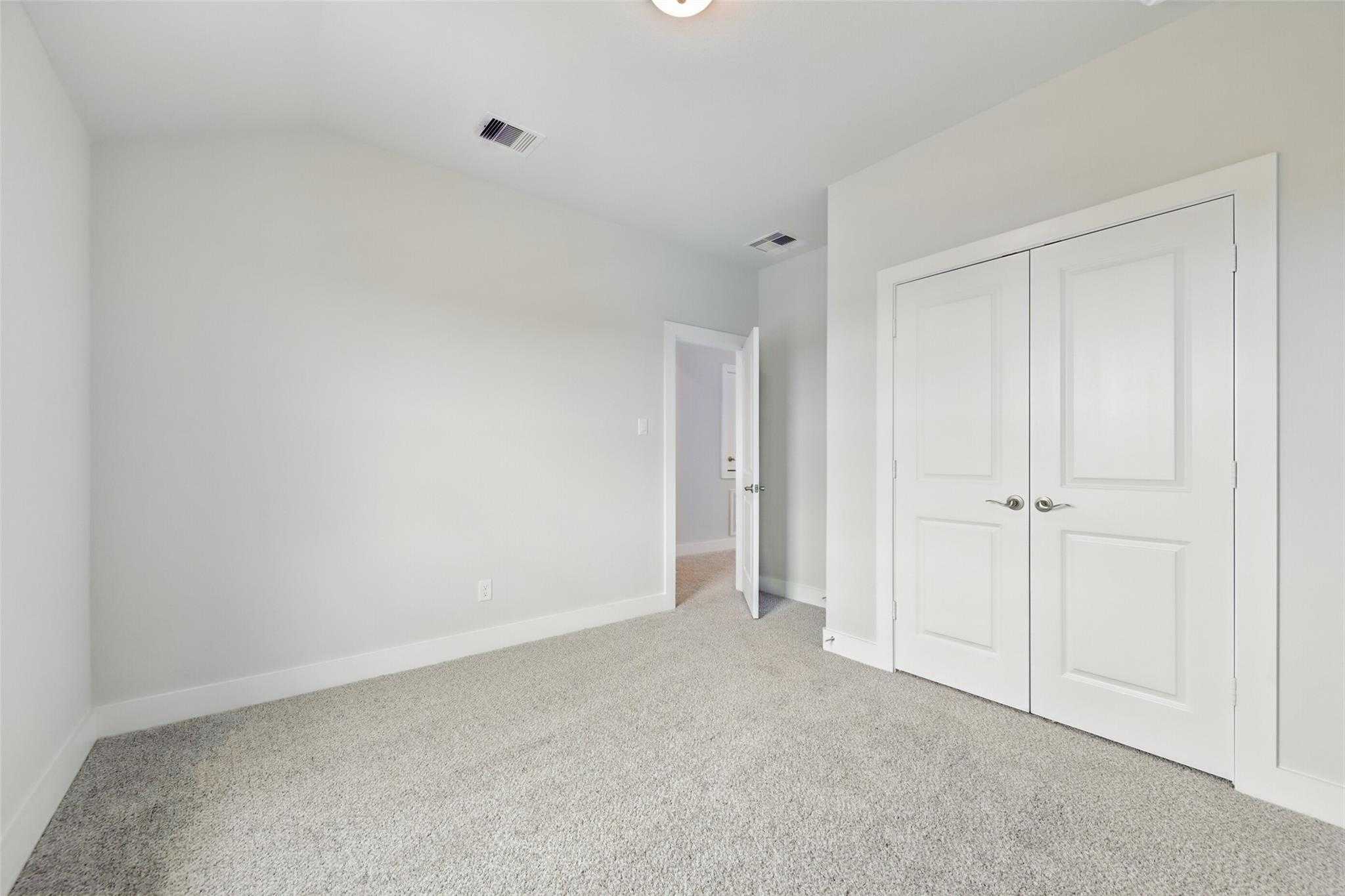 Spacious secondary bedroom with vaulted ceiling, beige carpet, and double closet doors in Davidson Homes The Philip A, Lago Mar, Texas City