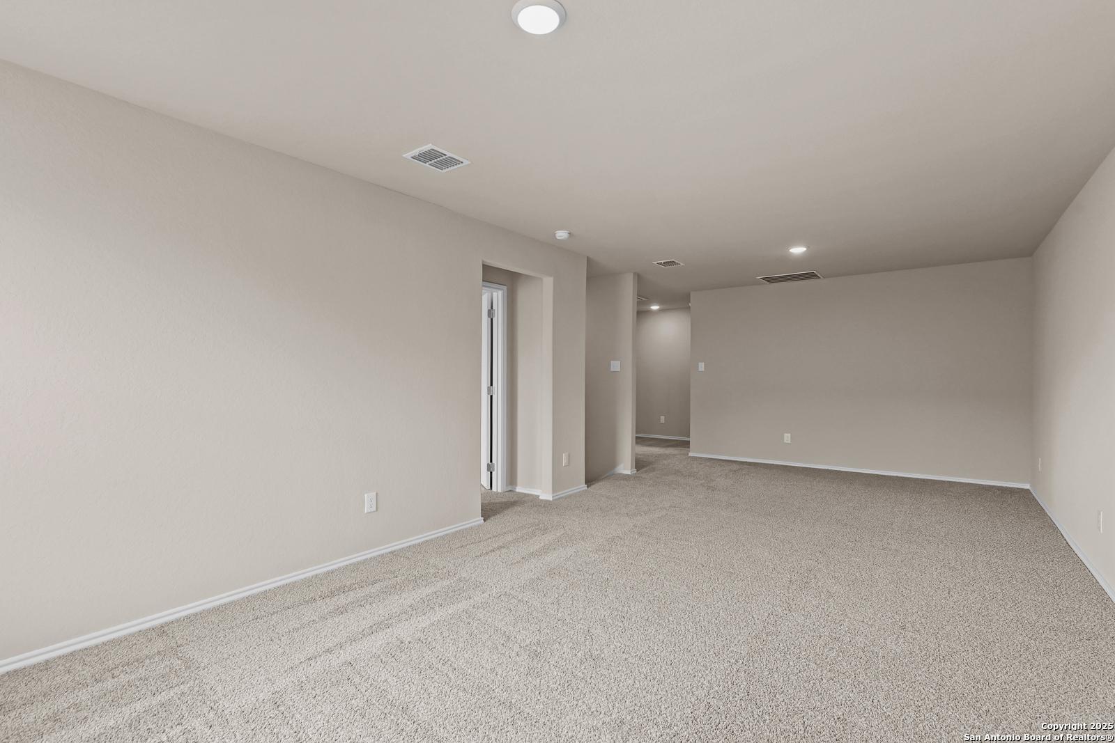 Spacious carpeted hallway with beige walls, recessed lights, and open doorways in Davidson Homes The Douglas G, Royal Crest, San Antonio