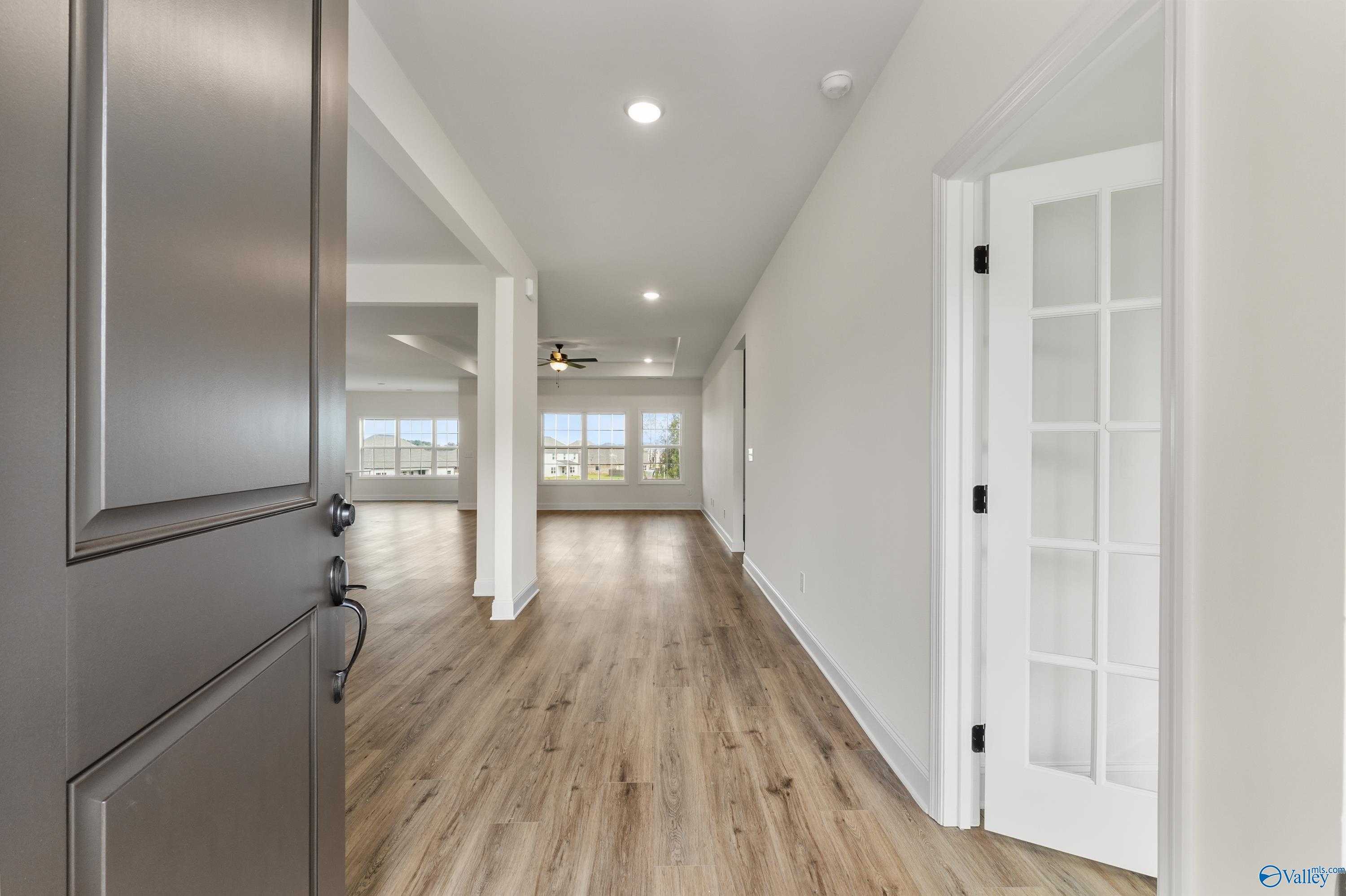 Bright entry hallway with luxury vinyl plank floors, white walls, recessed lights, and large windows in Davidson Homes The Finleigh, Creekside, Harvest AL