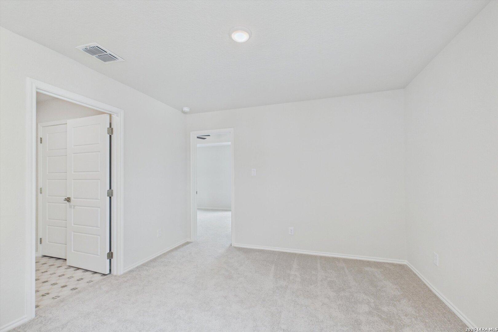 Bright, neutral-toned secondary bedroom with plush carpeting in The Charlotte B floor plan at Meadows at Oak Creek.