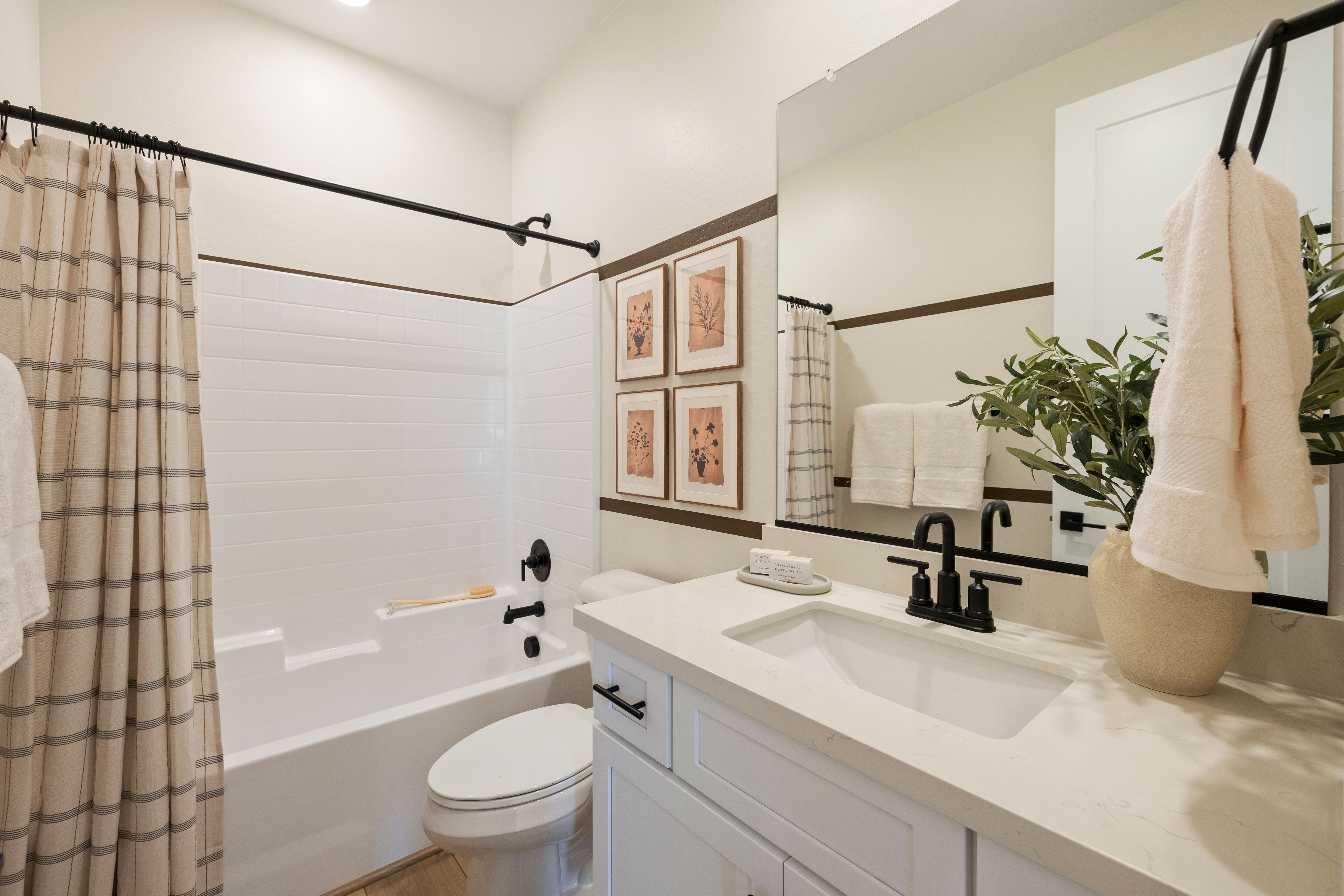 Modern bathroom with white subway tile shower tub black fixtures and olive branch decor at Vineyards at Cottonwood in Cottonwood AZ
