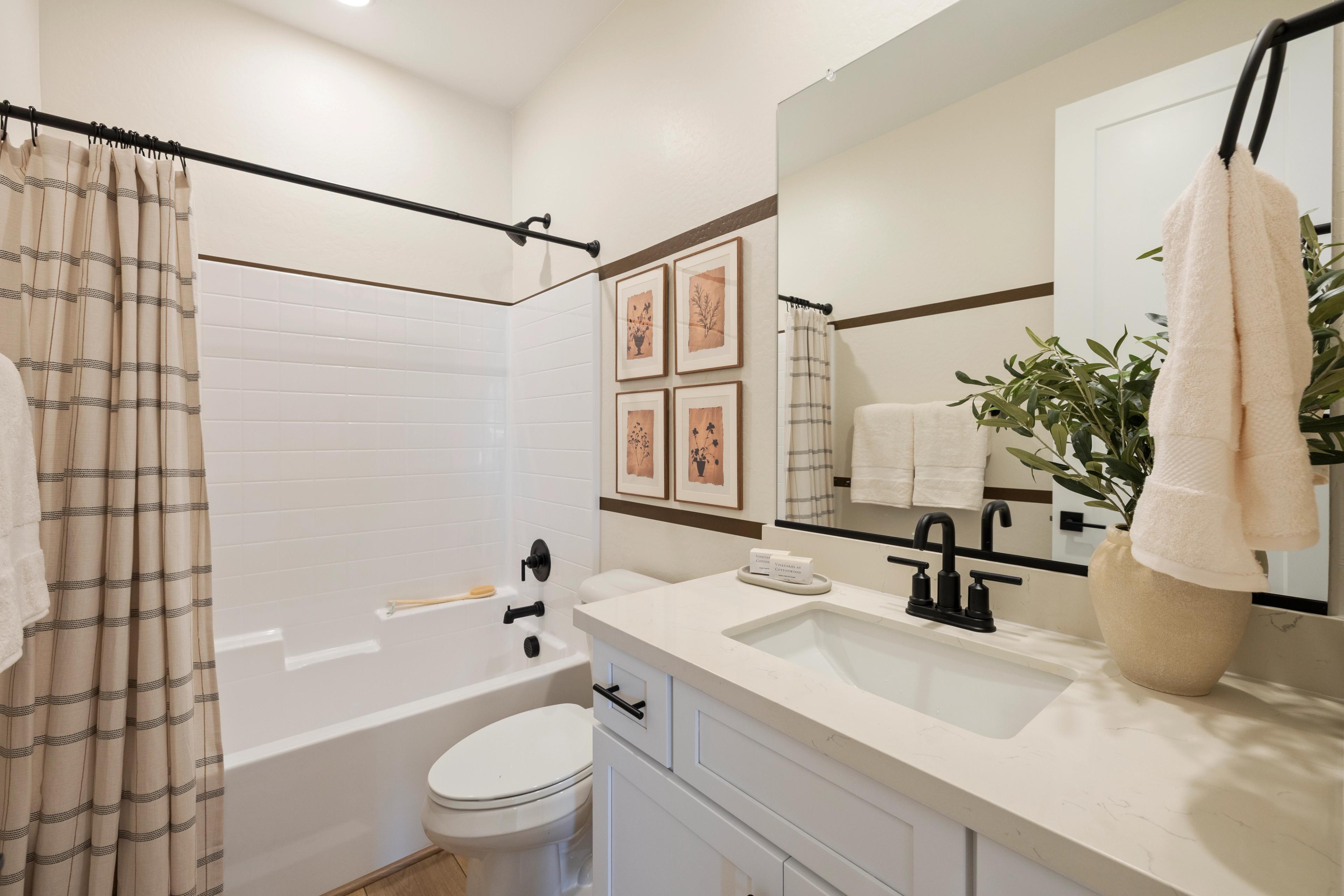 Modern bathroom with white subway tile shower tub black fixtures and olive branch decor at Vineyards at Cottonwood in Cottonwood AZ