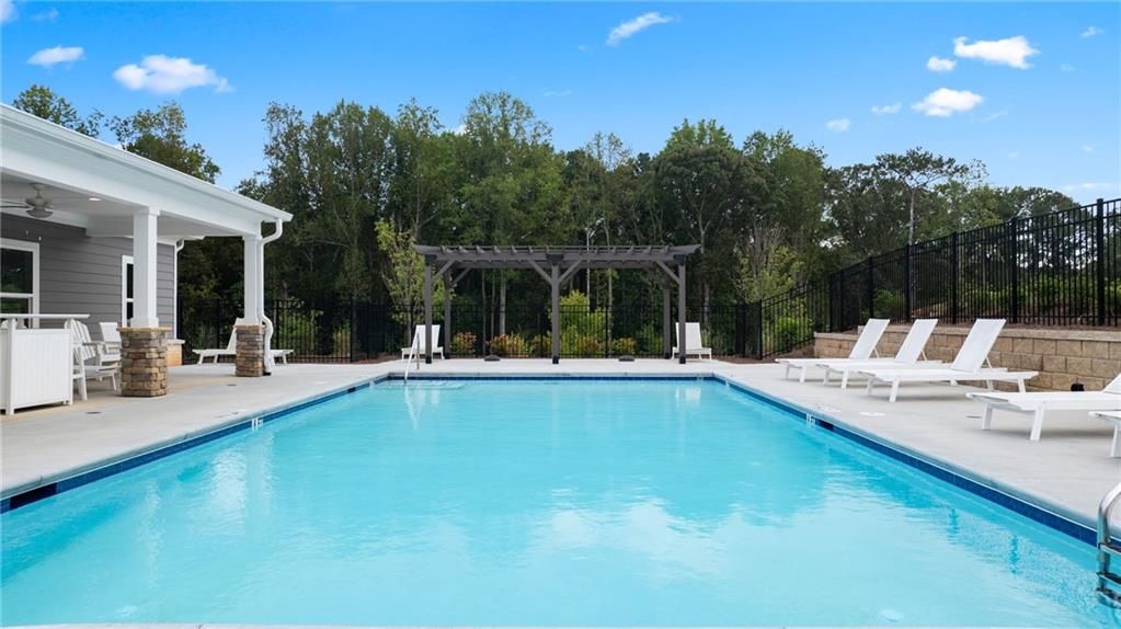 Community pool with white lounge chairs, wooden pergola, and lush trees in Kelly Preserve, Loganville, Georgia