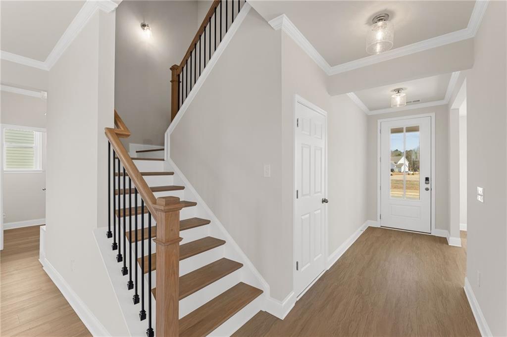 Elegant oak staircase with black wrought iron balusters in light gray foyer of Davidson Homes Willow B, Hoschton, Georgia