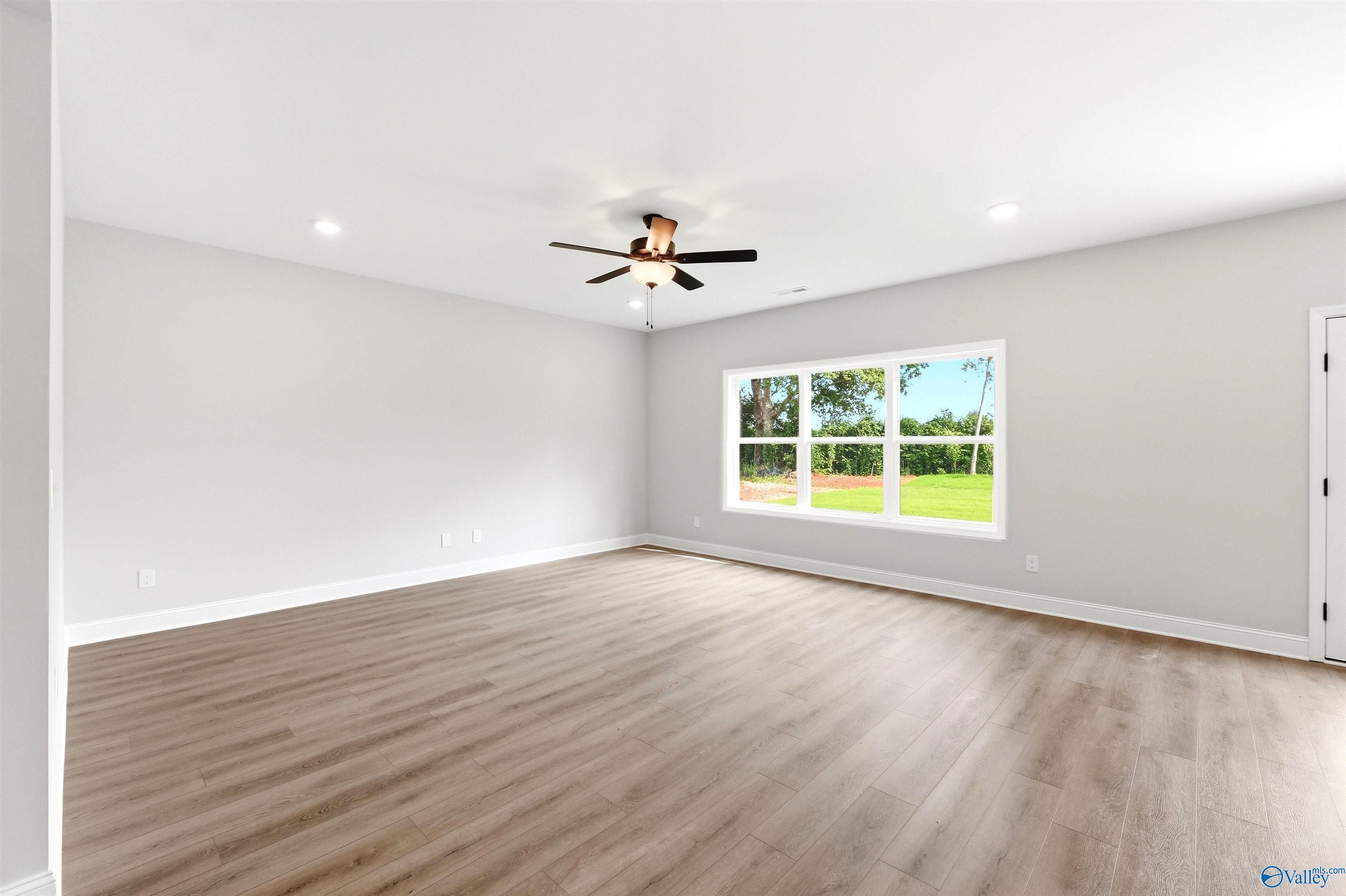 Spacious, light-filled bedroom with wood-look flooring in The Chelsea D floor plan at Berry Cove in New Market, Alabama.