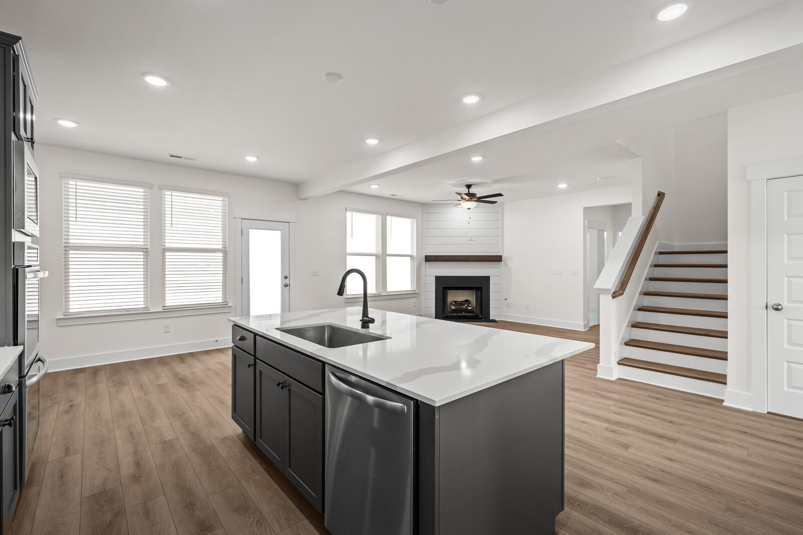Open-concept kitchen with large island and fireplace in The Willow floor plan at Woods Crossing, Gallatin, Tennessee.