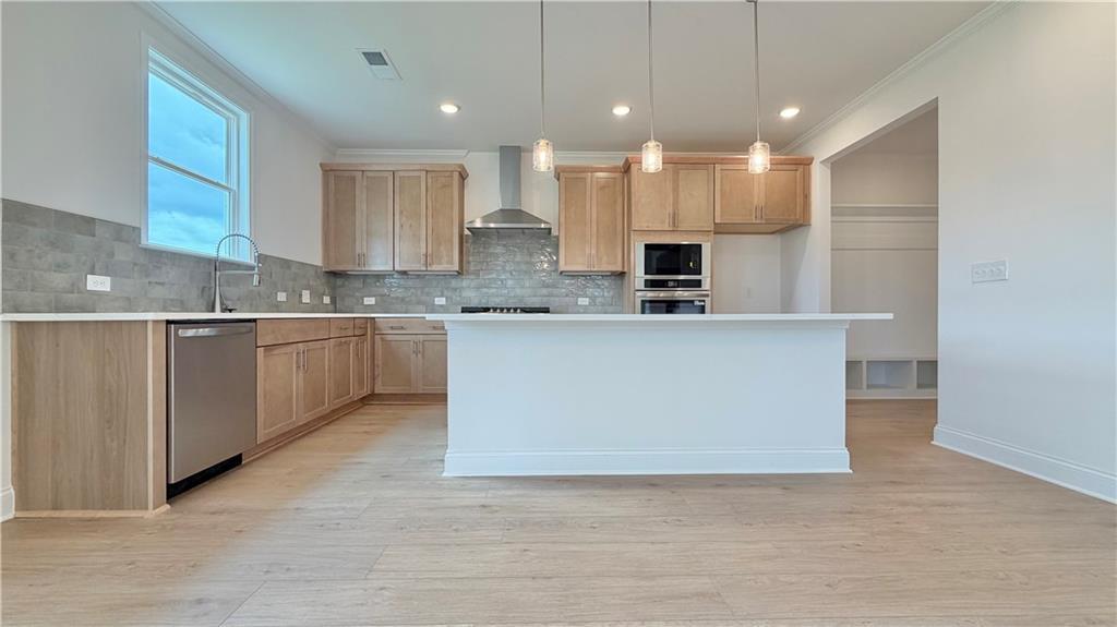 Modern kitchen with island, light wood cabinets, and stainless appliances in The Hickory C plan, Wehunt Meadows, Hoschton.