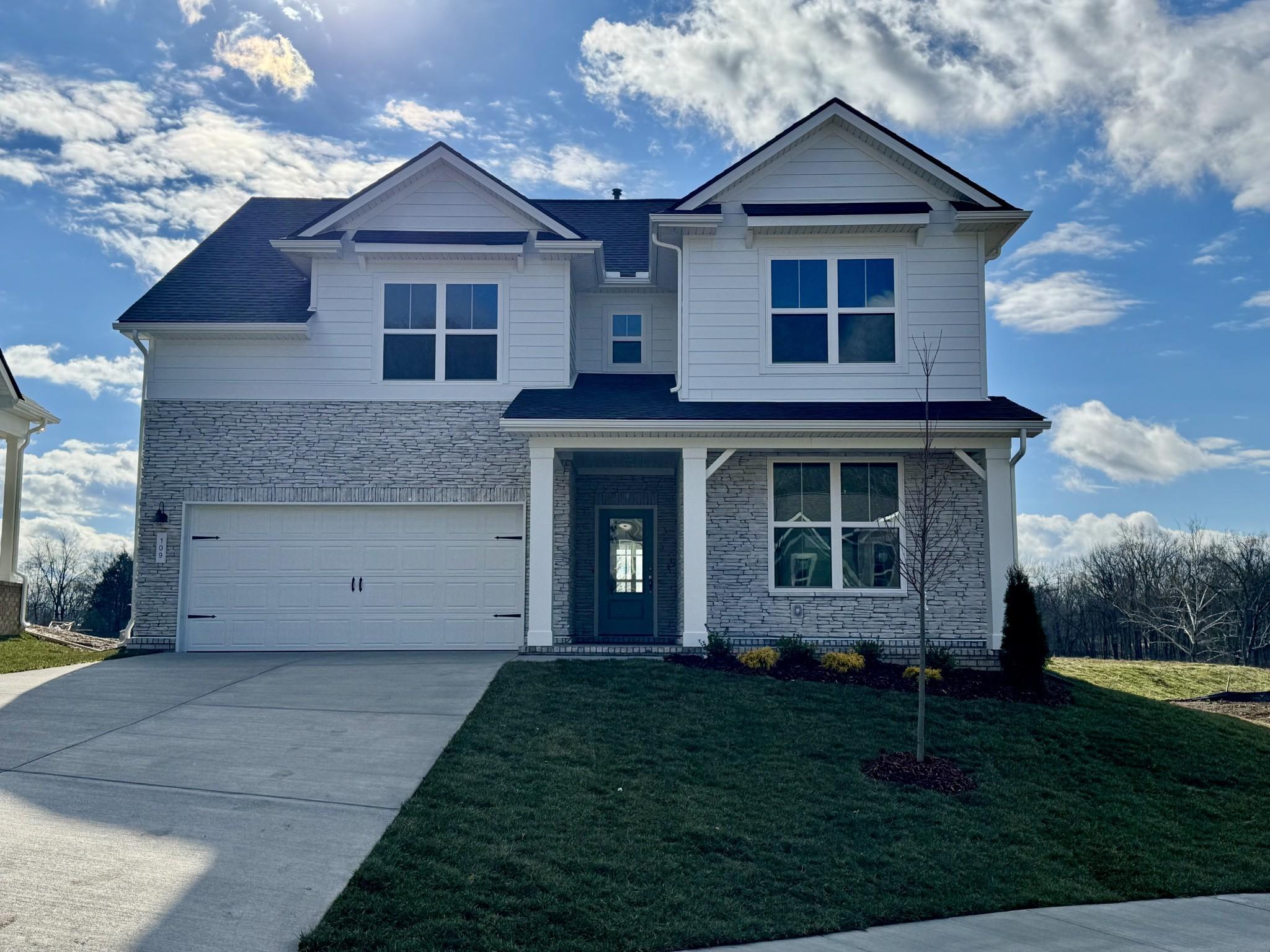 Modern two-story Ridgeport home with white siding, gray brick accents, two-car garage, and manicured lawn in Woods Crossing, Gallatin, Tennessee