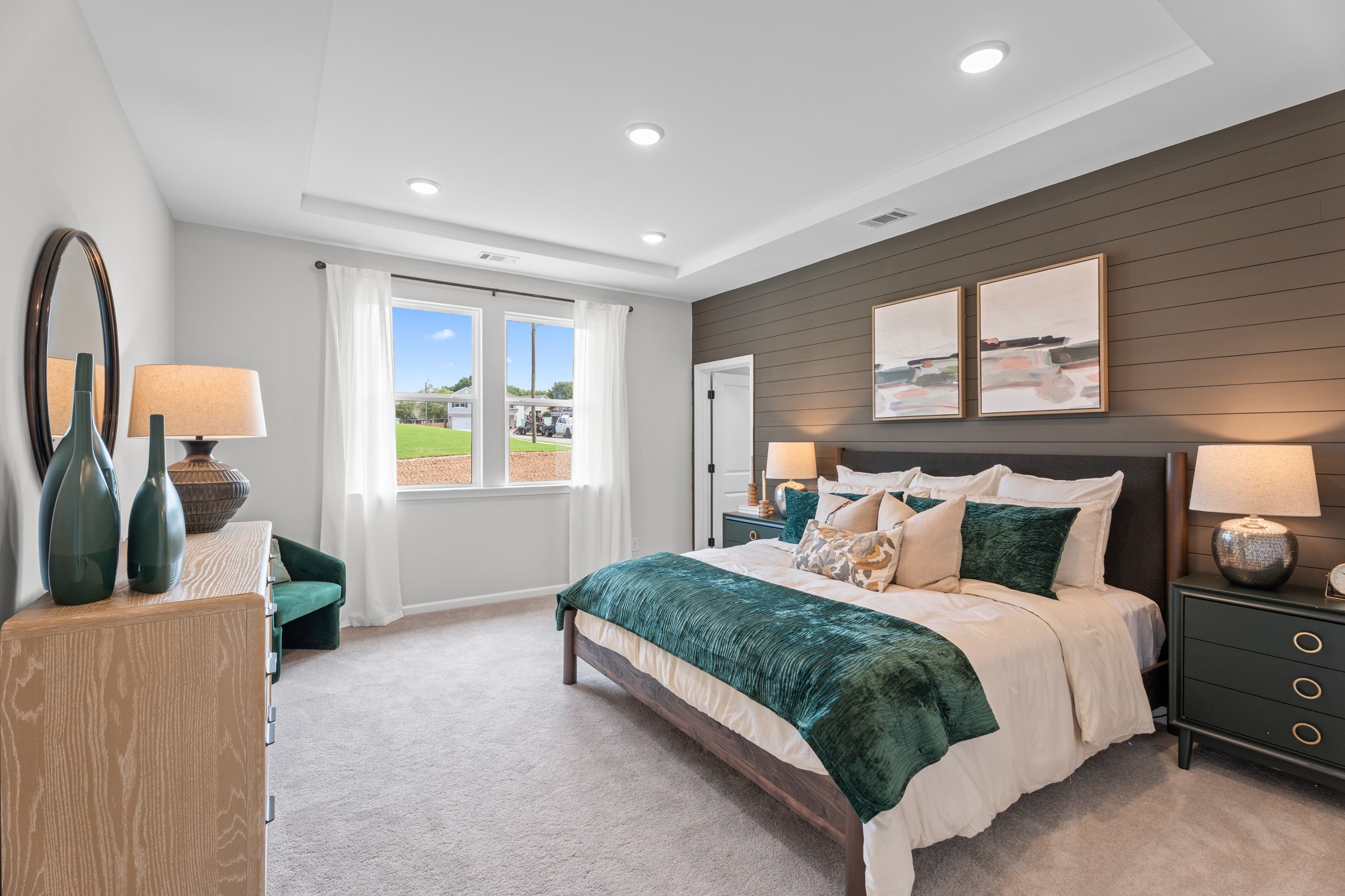 Spacious primary bedroom at Links Crossing in Auburn, AL by Davidson Homes with wood accent wall and green velvet bedding.