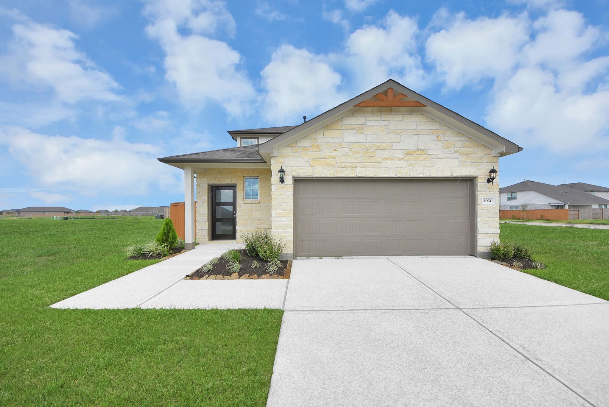 New construction home exterior with stone facade and 2-car garage in Emberly, Beasley, Texas by Davidson Homes