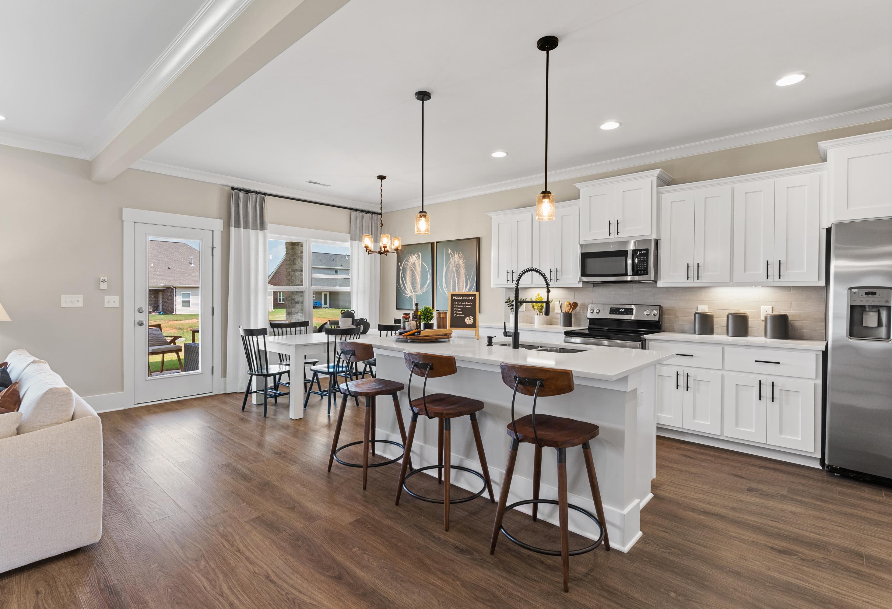 Spacious open-concept kitchen in The Shelby A with white cabinetry, large island, stainless appliances, and adjacent dining area