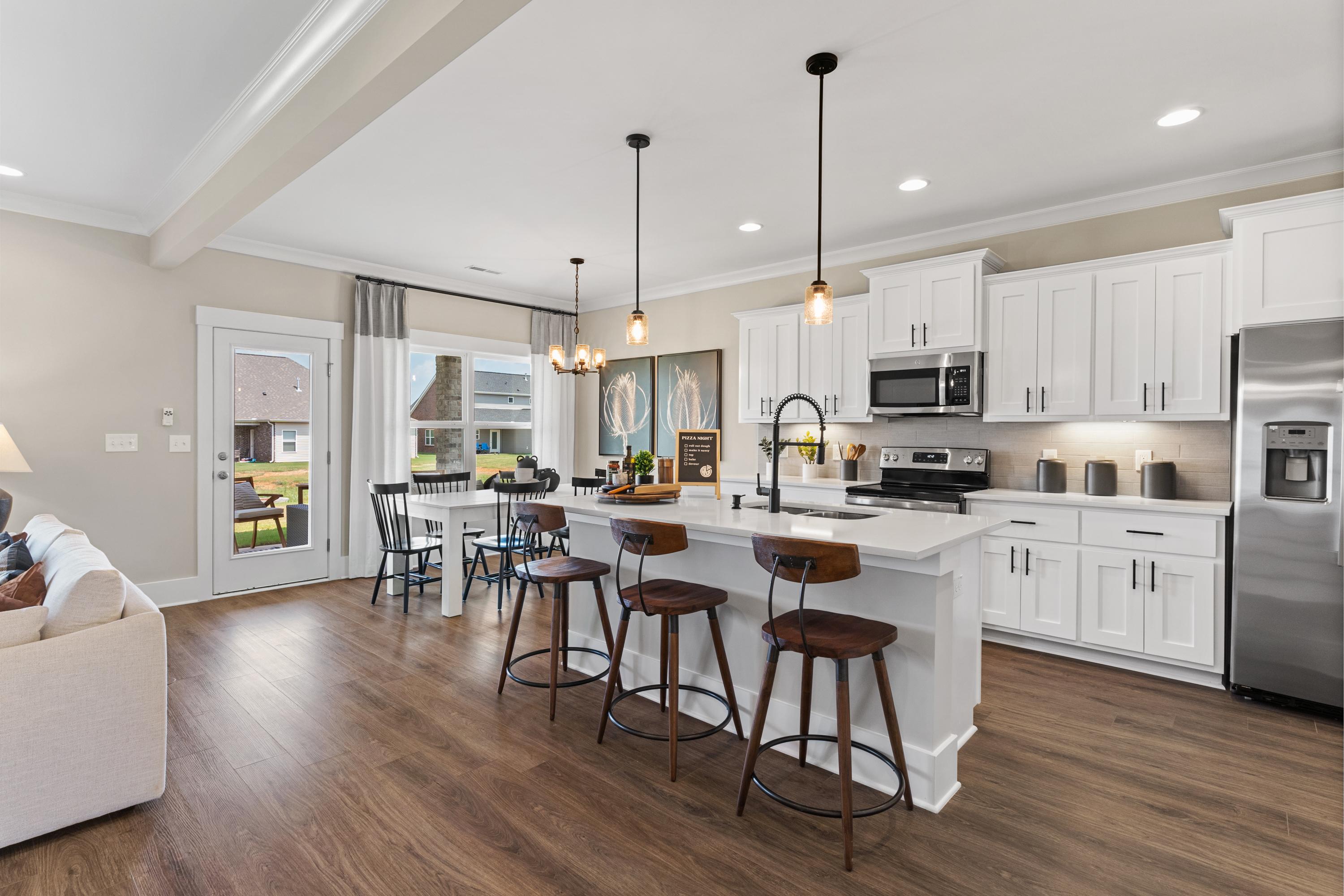 Spacious open-concept kitchen in The Shelby A with white cabinetry, large island, stainless appliances, and adjacent dining area