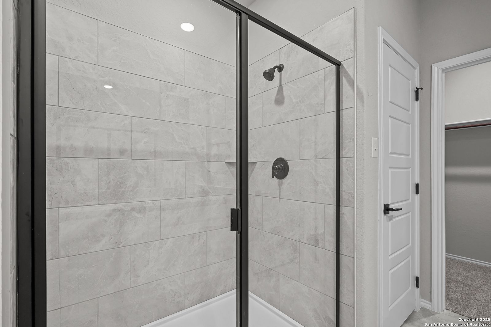 Modern frameless glass shower with gray subway tiles and rainfall head in master bath of Davidson Homes The Daphne K, San Antonio