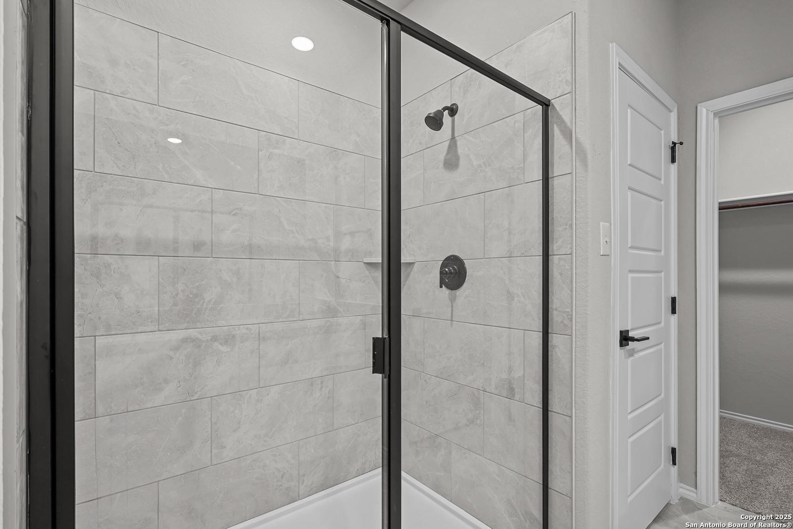 Modern frameless glass shower with gray subway tiles and rainfall head in master bath of Davidson Homes The Daphne K, San Antonio