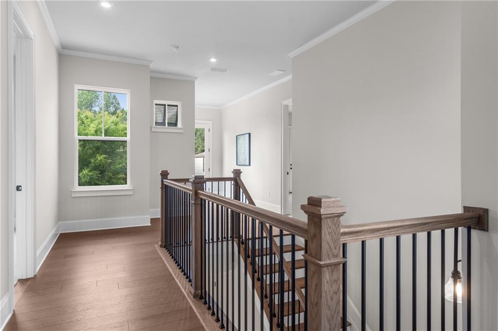 Elegant upstairs hallway with oak staircase, hardwood floors, and large windows in Davidson Homes The Seaside B, Woodstock, Georgia