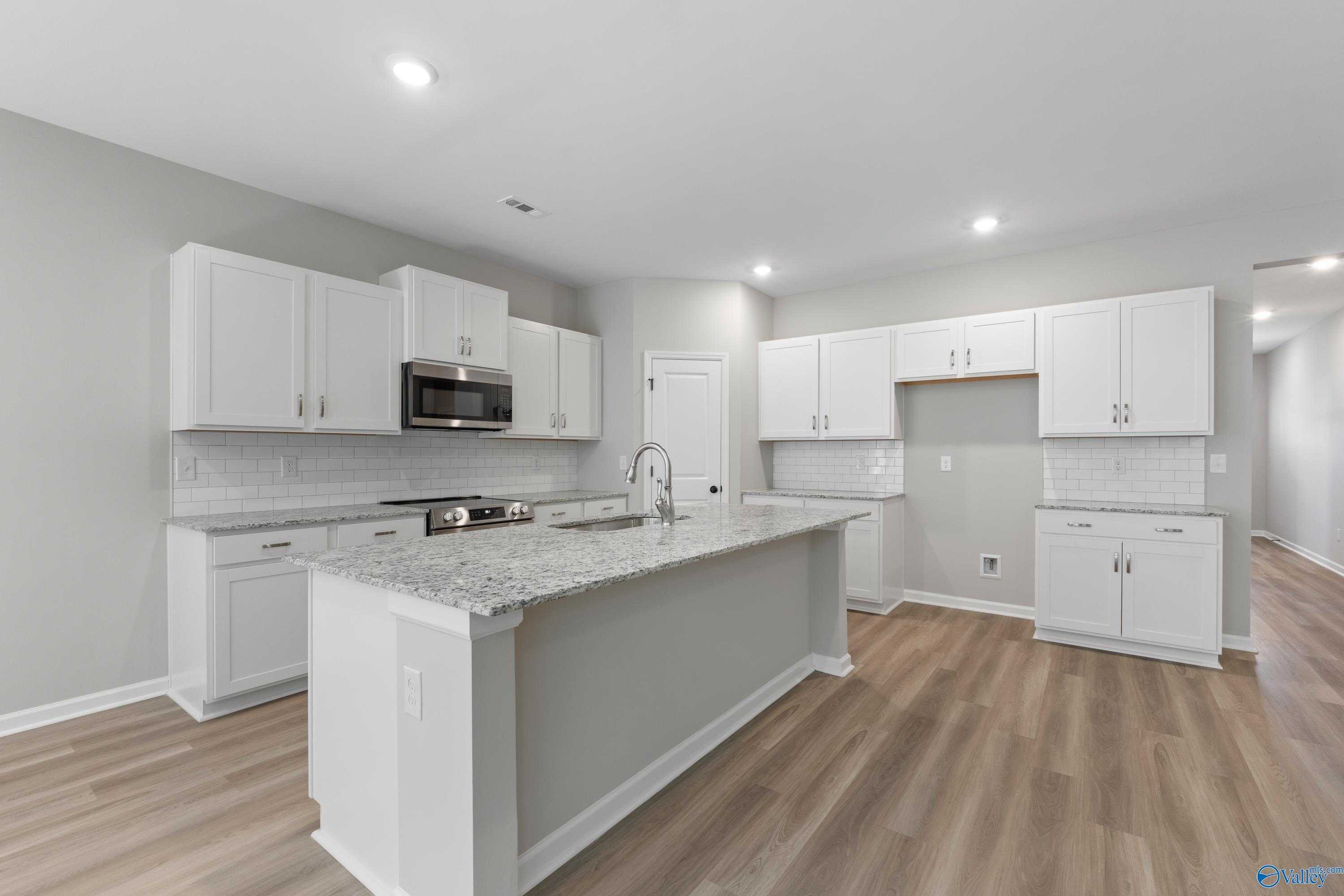 Modern white kitchen with granite island, stainless appliances, subway tile backsplash in The Phoenix floor plan, Davidson Homes, Fayetteville, TN