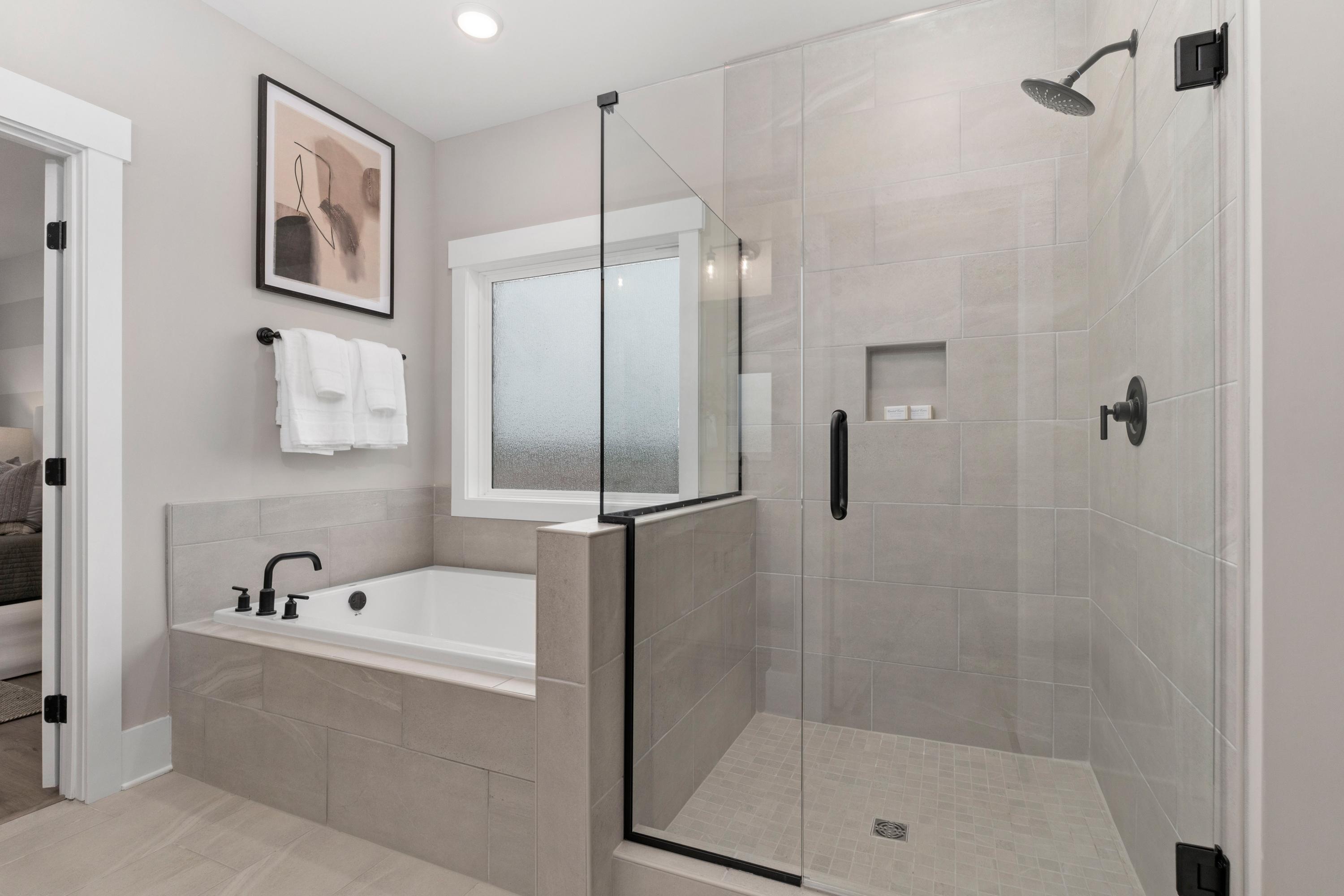 Spacious master bathroom at Little Creek in Arab, Alabama with frameless glass shower, soaking tub, and neutral tile finishes