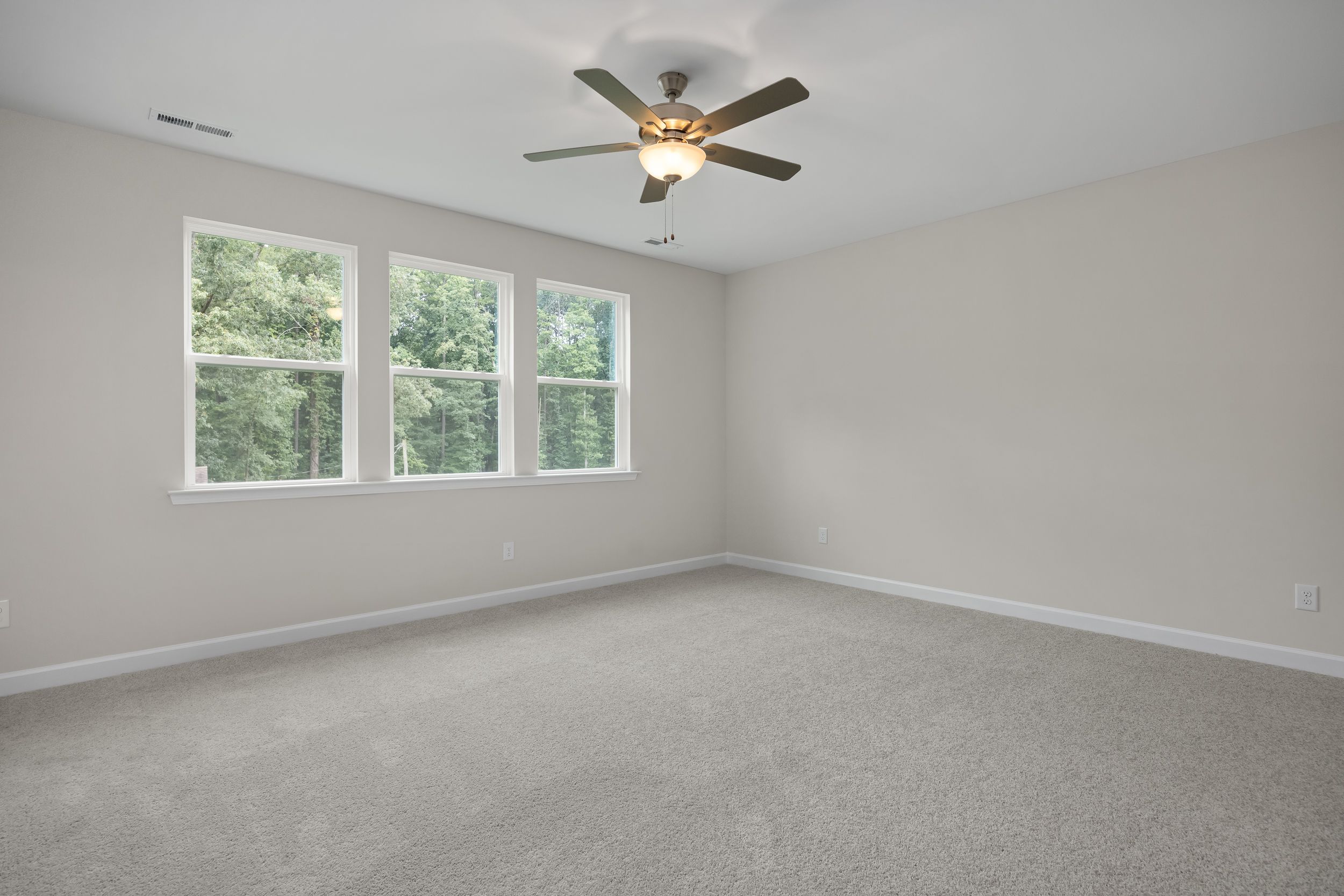 Spacious upper-floor bedroom in The Beech A home design featuring light gray walls, three large windows, ceiling fan, and beige carpet