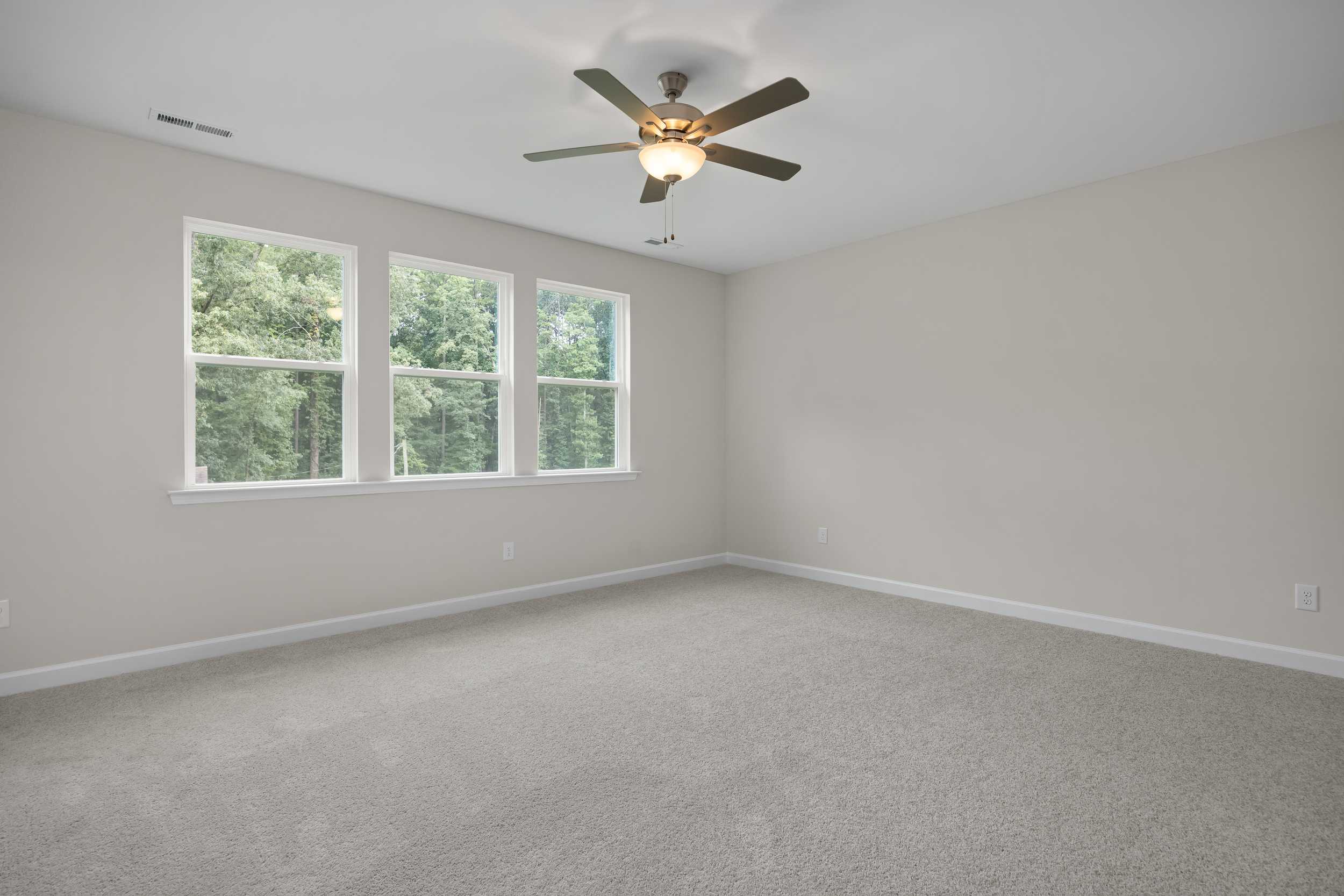 Spacious Beech C upper bedroom featuring beige walls, three large windows with tree views, ceiling fan, and carpeted floor