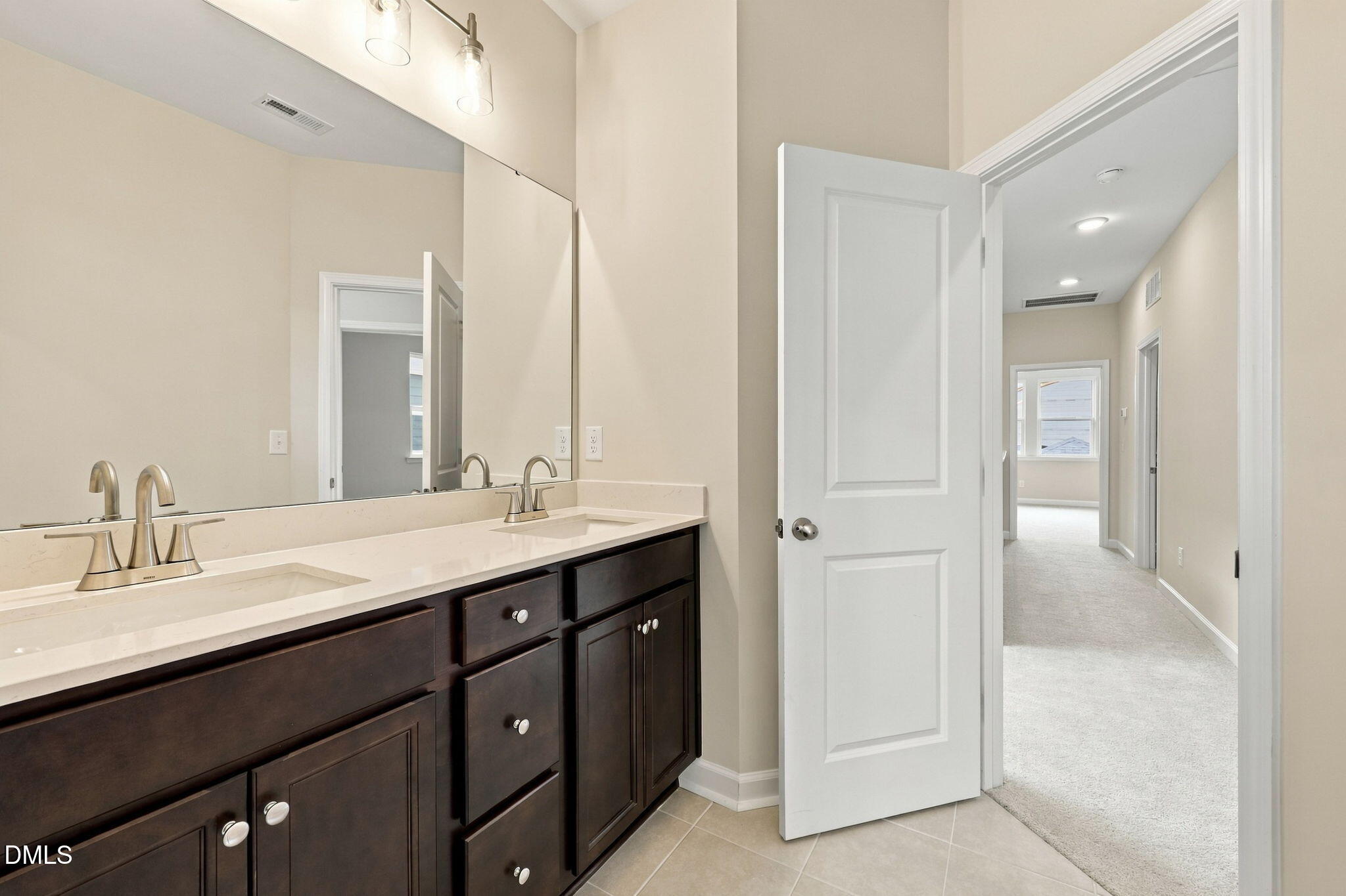 Double vanity bathroom with dark wood cabinets, large mirror, and brushed nickel faucets in Davidson Homes The Alexander B, Knightdale NC