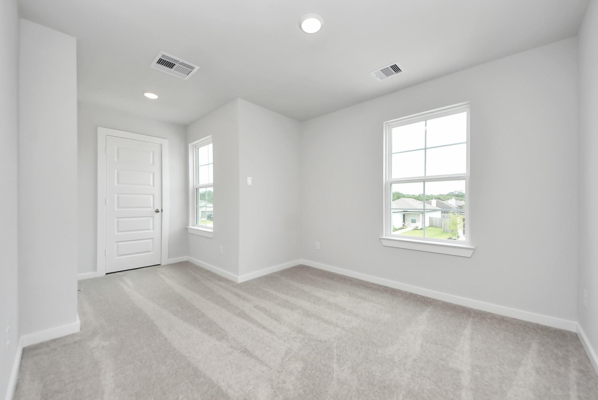 Bright, carpeted bedroom with white walls and natural light in The Blanco E floor plan at The Villages at WestPointe.