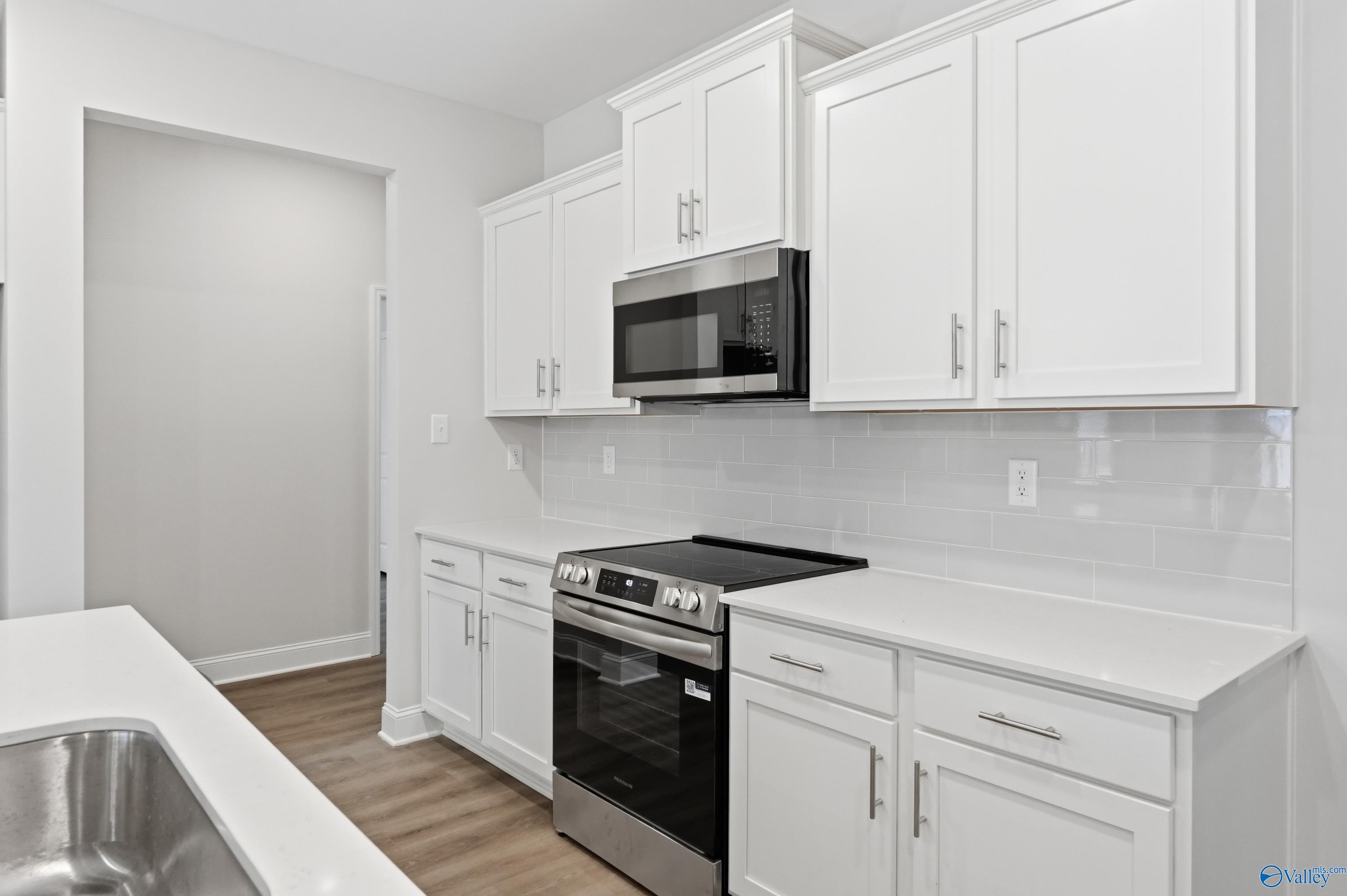 Modern white kitchen with stainless appliances, quartz counters, subway tile backsplash in Davidson Homes The Cumberland, Decatur, AL
