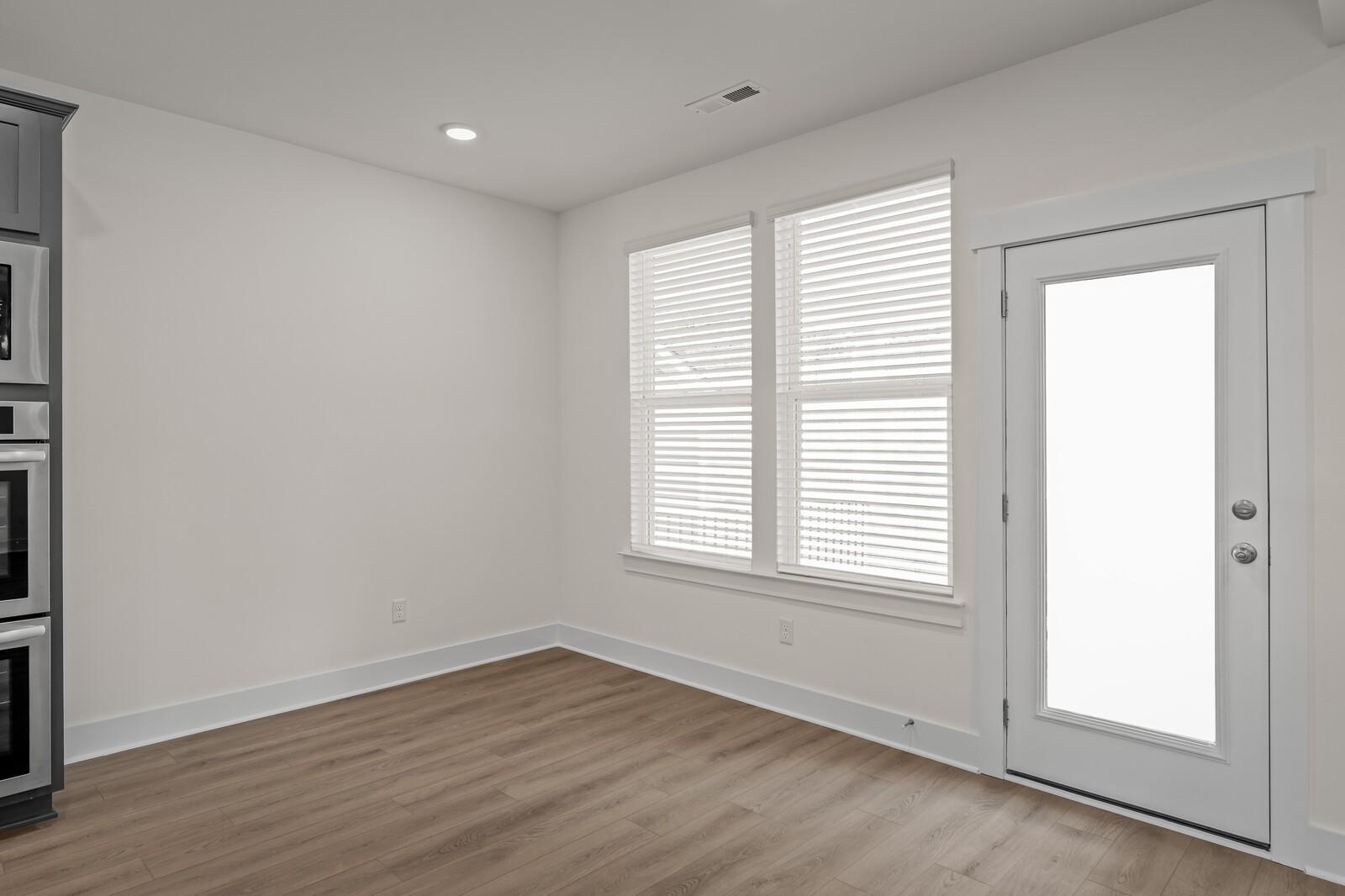 Bright breakfast nook with wood-look flooring and backyard access in The Willow floor plan at Woods Crossing, Gallatin.