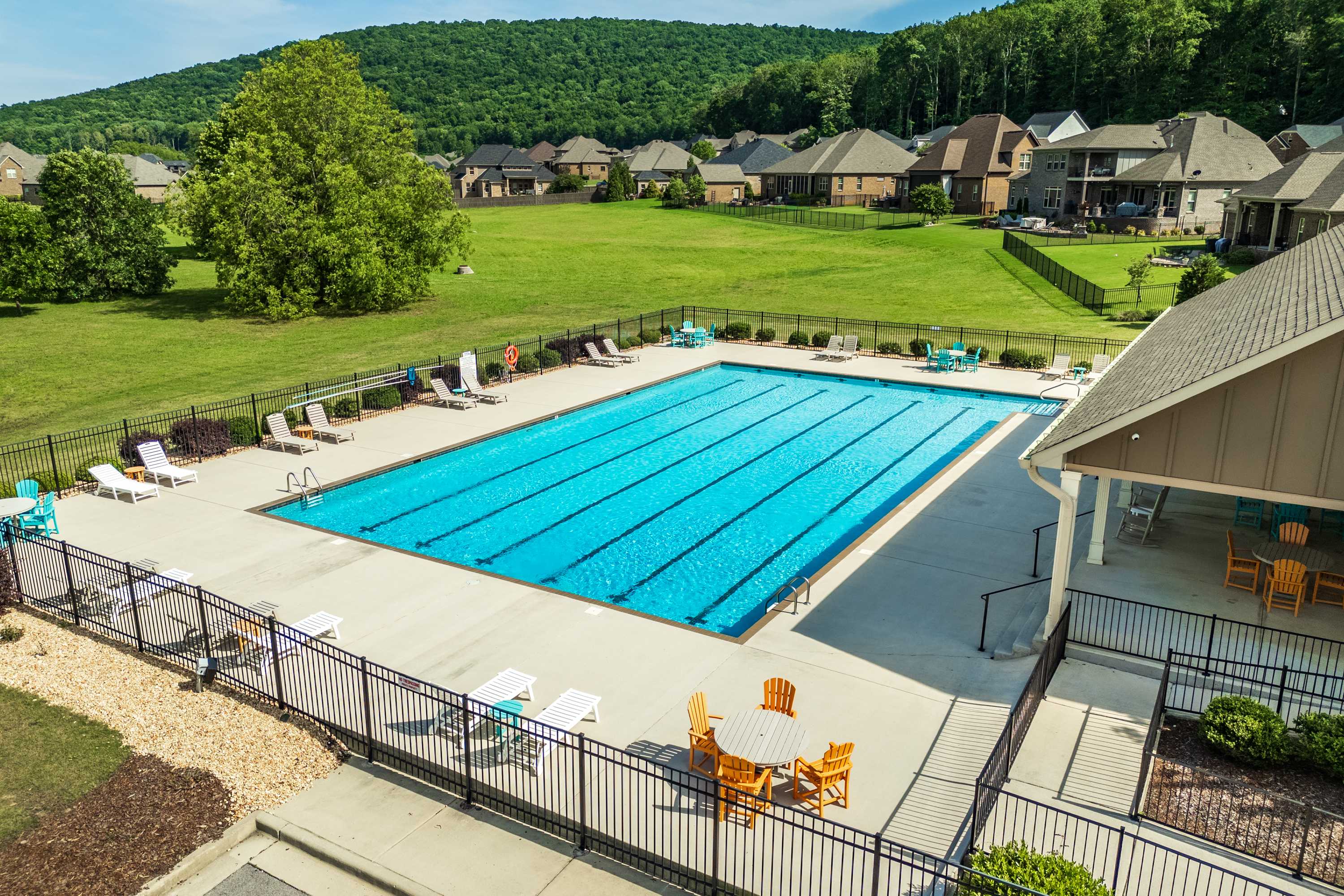 Resort-style swimming pool at The Meadows at Hampton Cove in Owens Cross Roads AL with lounge chairs, pavilion and scenic green backdrop