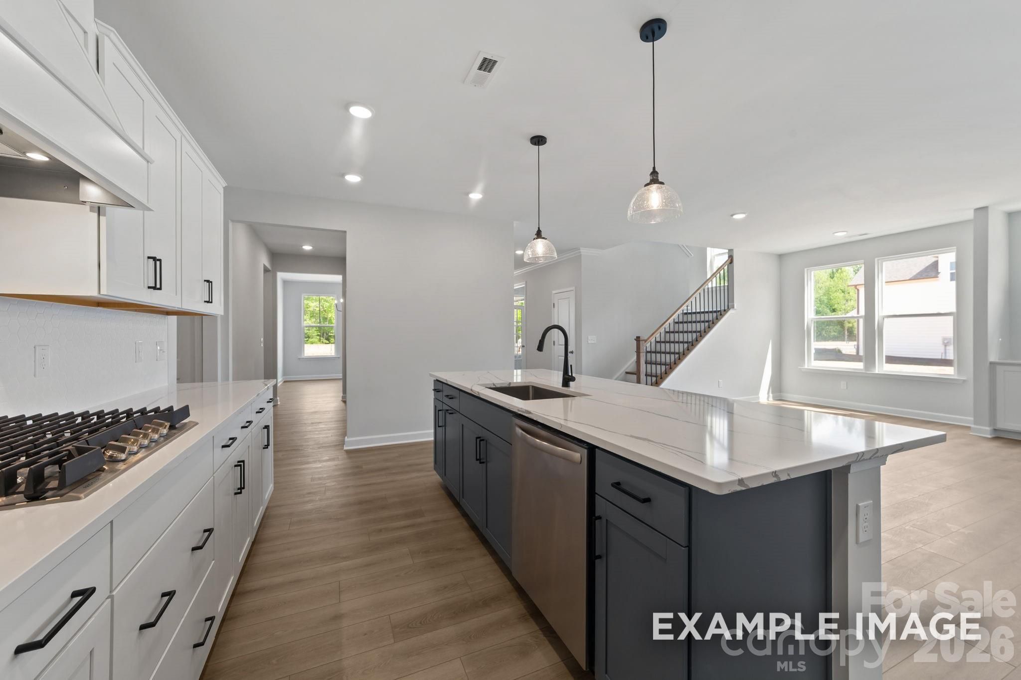 Modern kitchen with charcoal island, white cabinets, and quartz countertops in Magnolia B floor plan, Windgate, Mooresville.