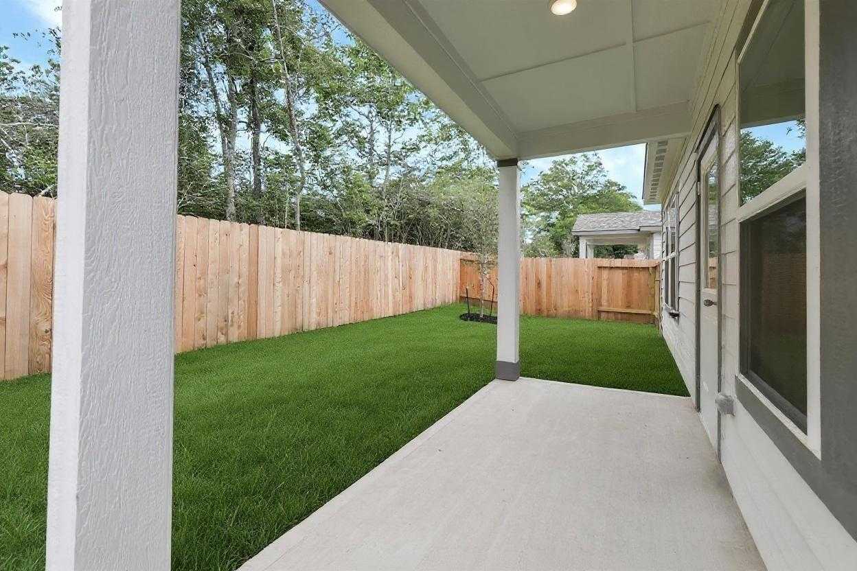 Covered patio with lush green lawn and wooden privacy fence in Davidson Homes The Frio G, Conroe, Texas