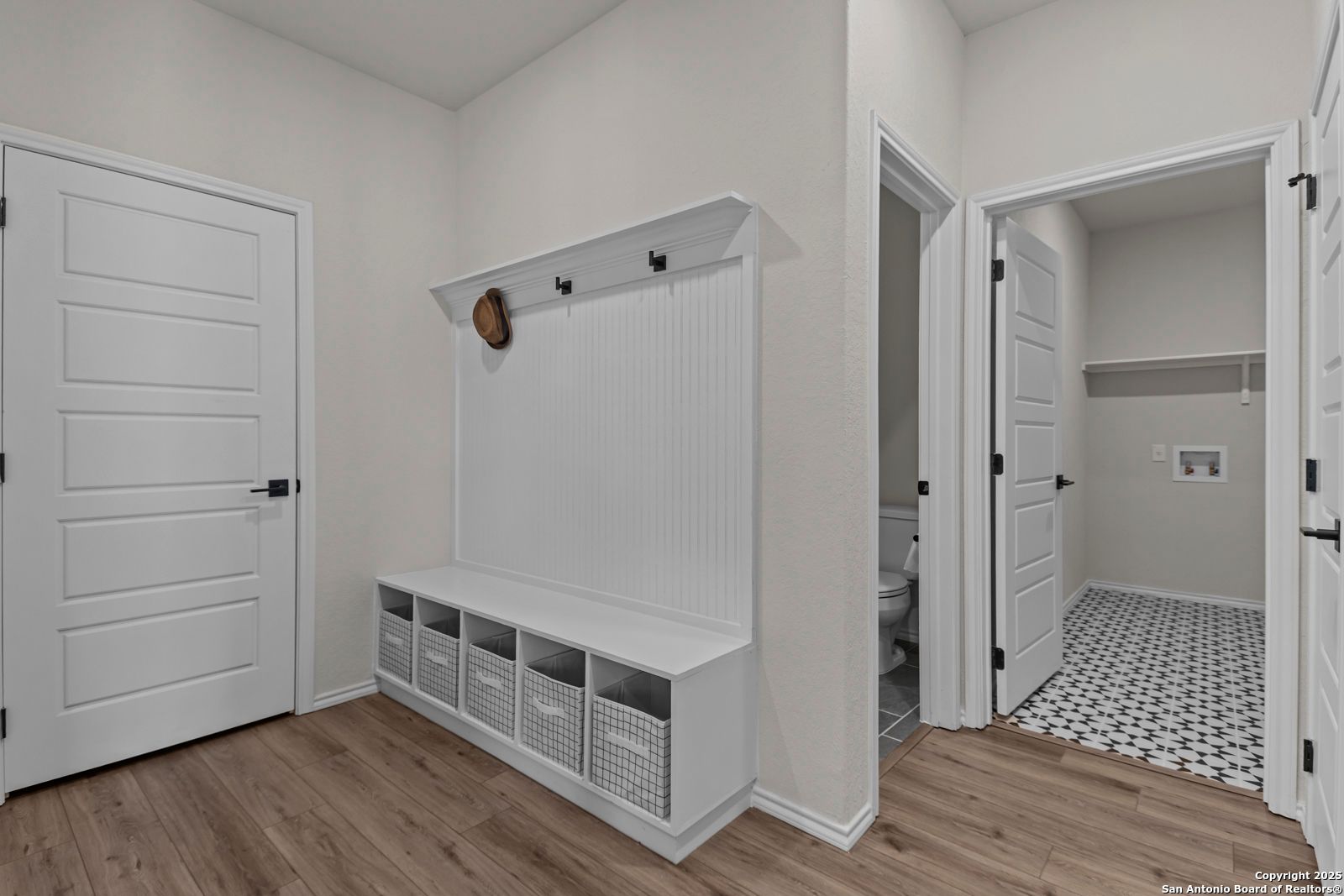 Functional mudroom with shiplap bench, storage cubbies, coat hooks, and powder room in Davidson Homes The Douglas C, Seguin, Texas