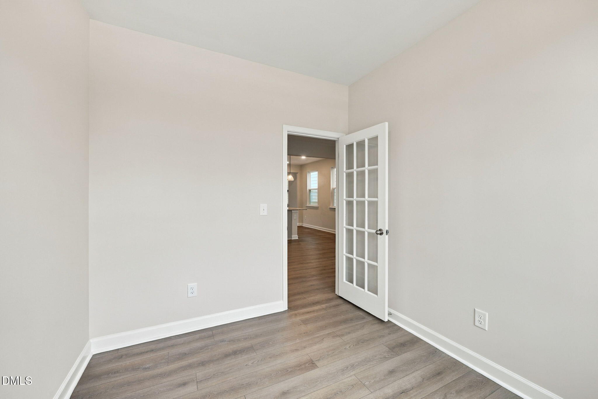 Empty flex room with glass-paneled French door and luxury vinyl plank flooring in Davidson Homes The Alexander B, Knightdale, NC