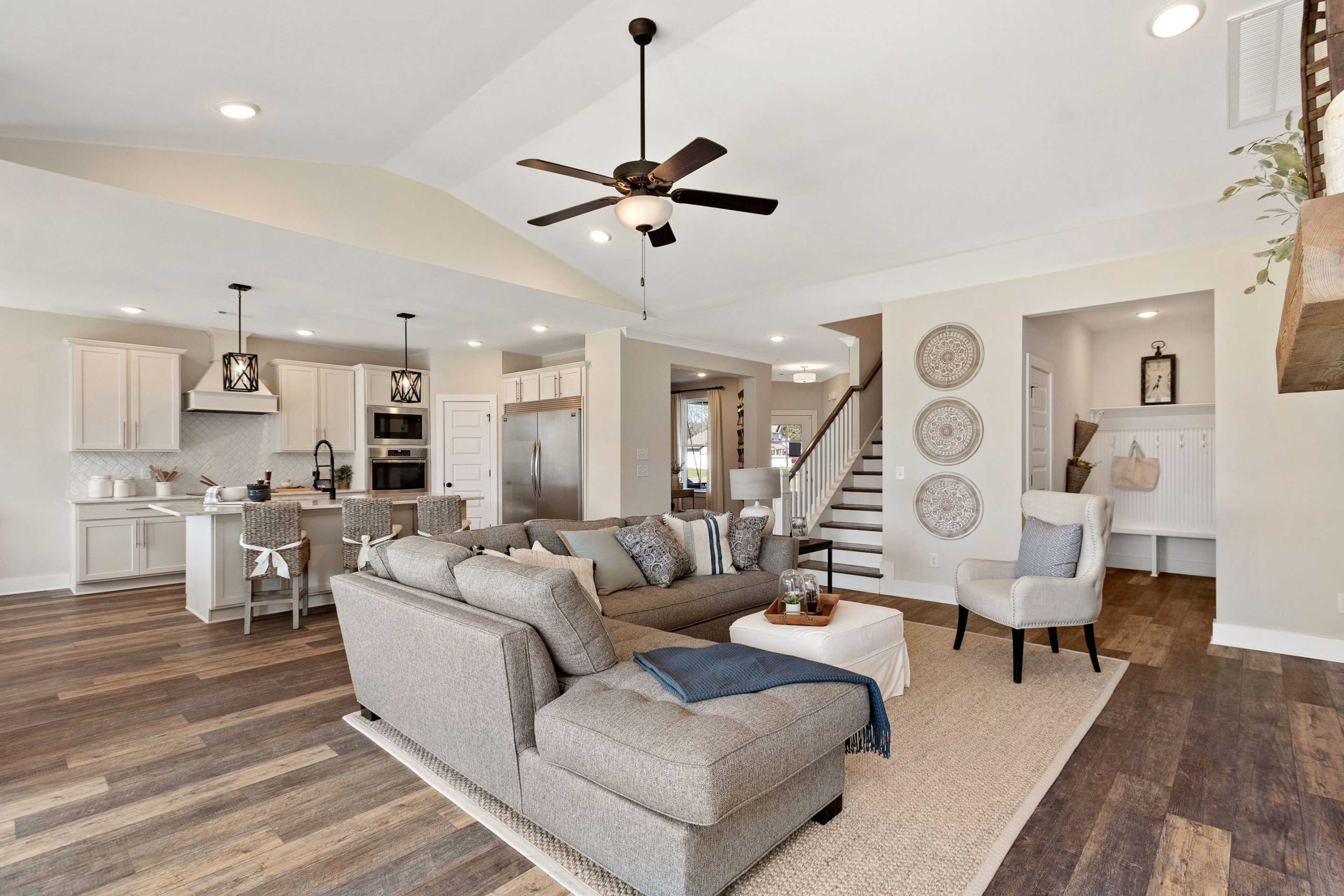 Open-concept living and kitchen at Rivers Edge in Murfreesboro TN with hardwood floors, gray sectional sofa, and ceiling fan