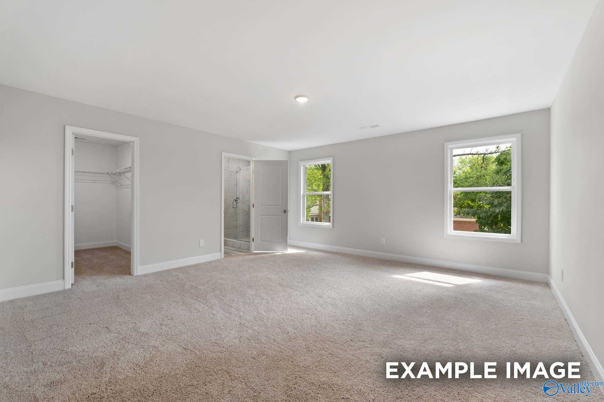 Bright secondary bedroom with walk-in closet, gray walls, and windows in Davidson Homes The Camden, Huntsville, AL