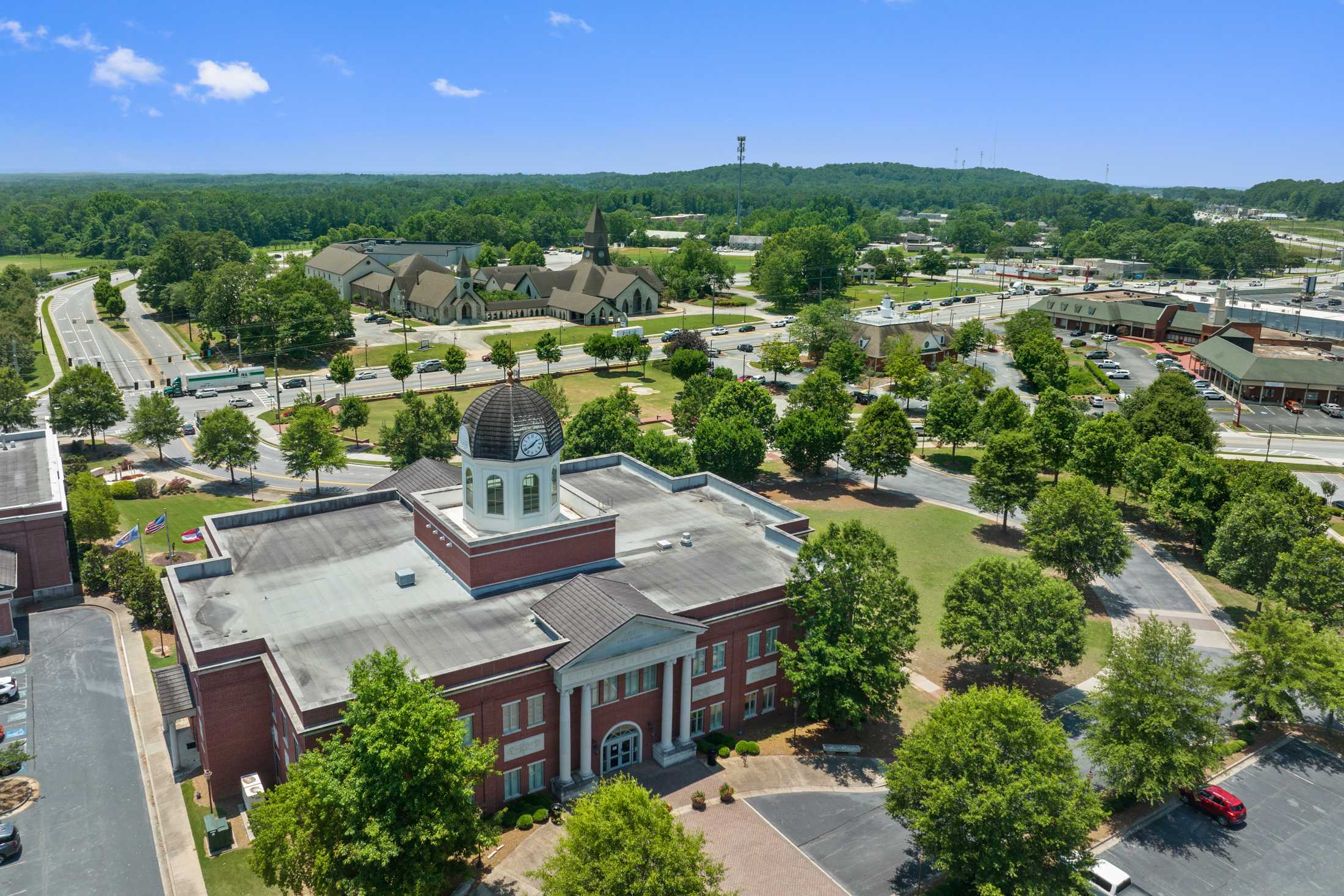 Aerial view of historic red brick courthouse with clock tower in Loganville Georgia near Kelly Preserve featuring green lawns trees and parking