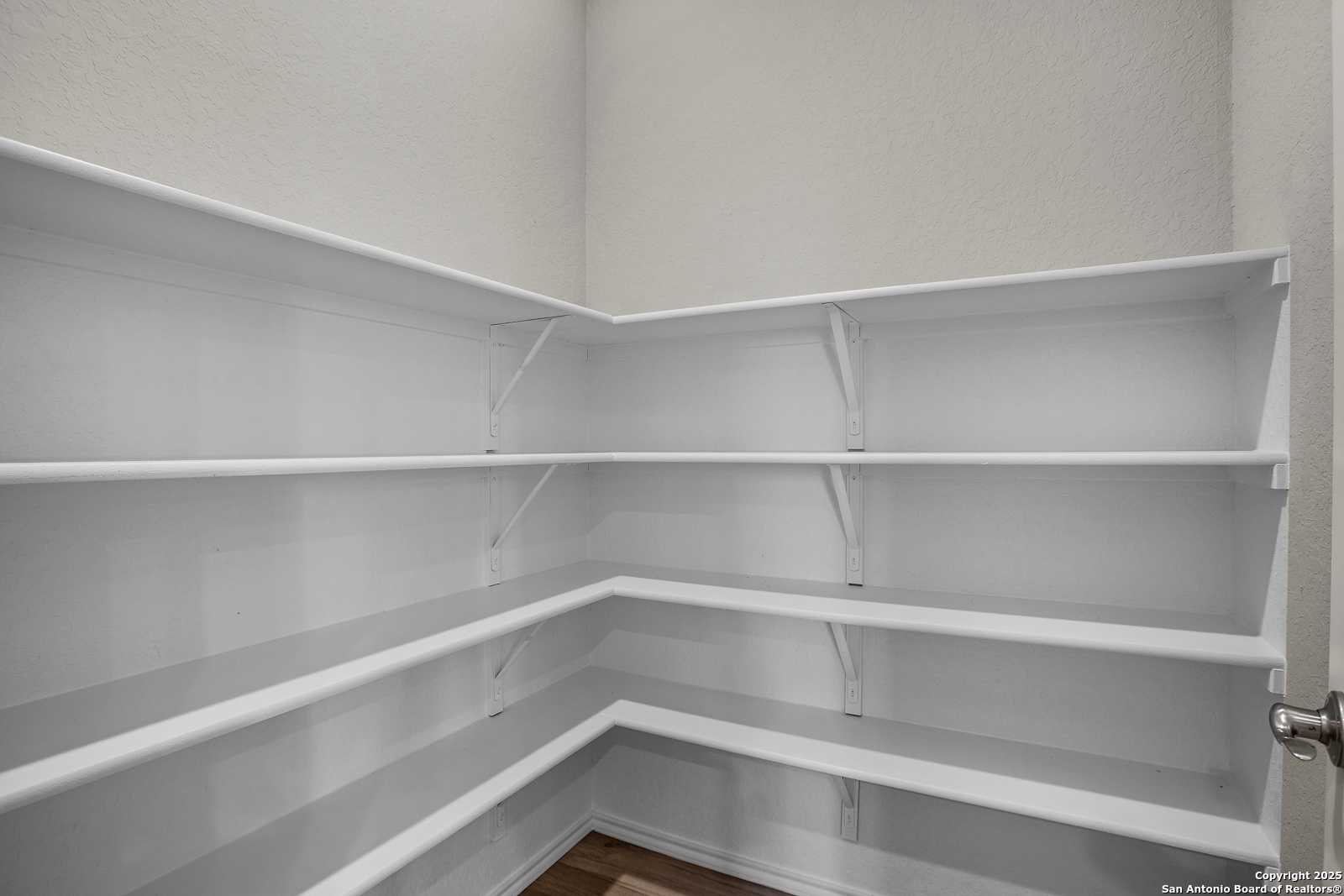 Spacious white corner pantry shelves in modern kitchen of The Collin B home by Davidson Homes, Seguin, Texas