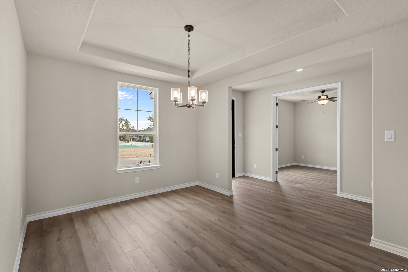 Formal dining room with tray ceiling and chandelier in The Danbury H model home at The Reserve at Potranco Oaks, TX.