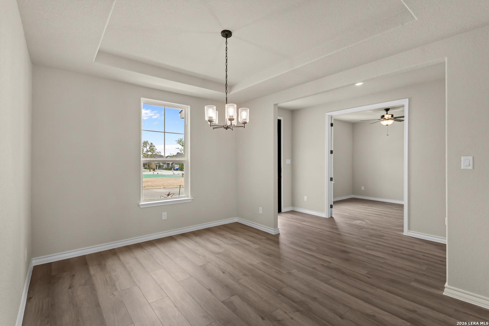 Formal dining room with tray ceiling and chandelier in The Danbury H model home at The Reserve at Potranco Oaks, TX.
