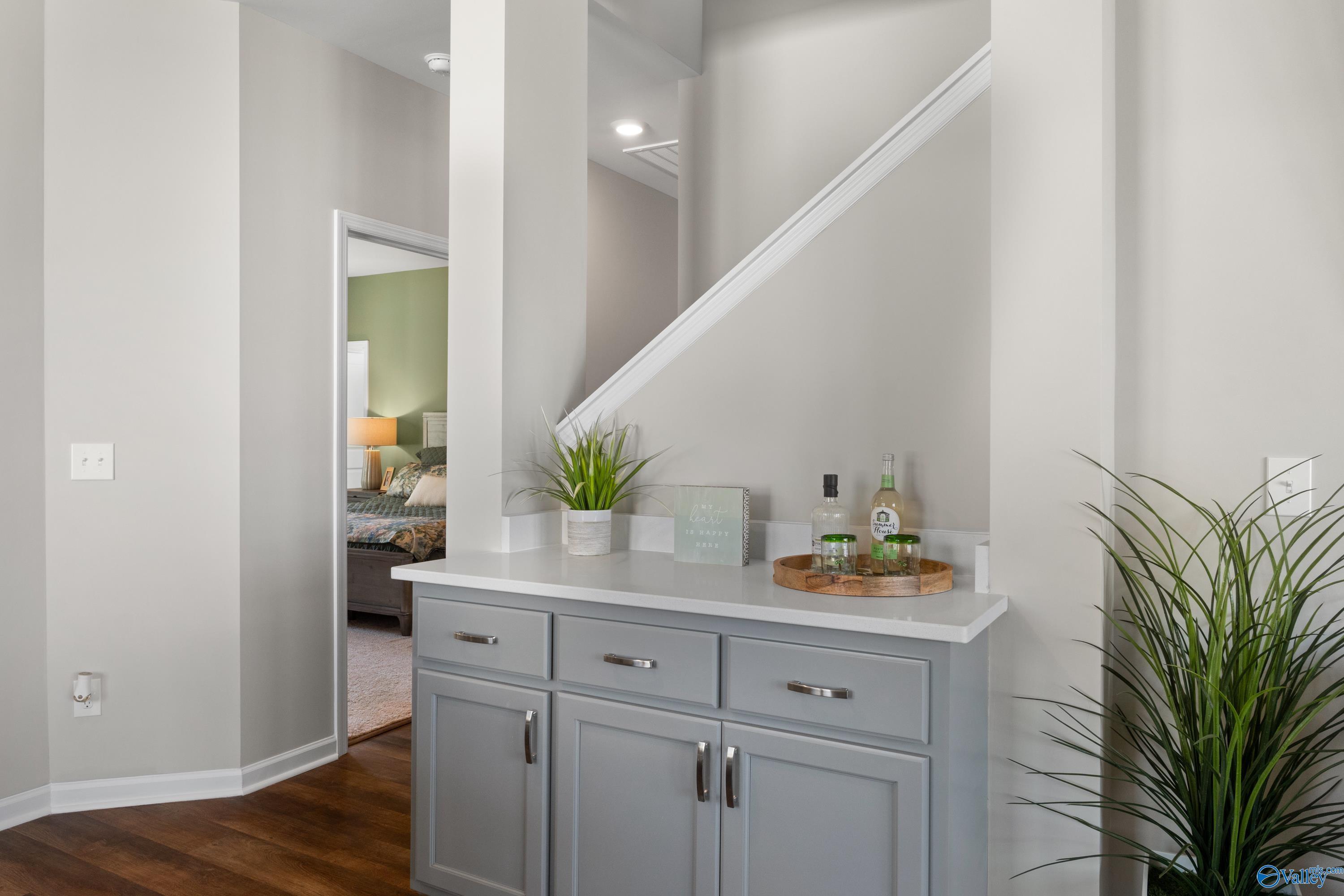 Elegant gray console cabinet with white quartz top, plants, and decor in Davidson Homes The Stella, Madison Alabama