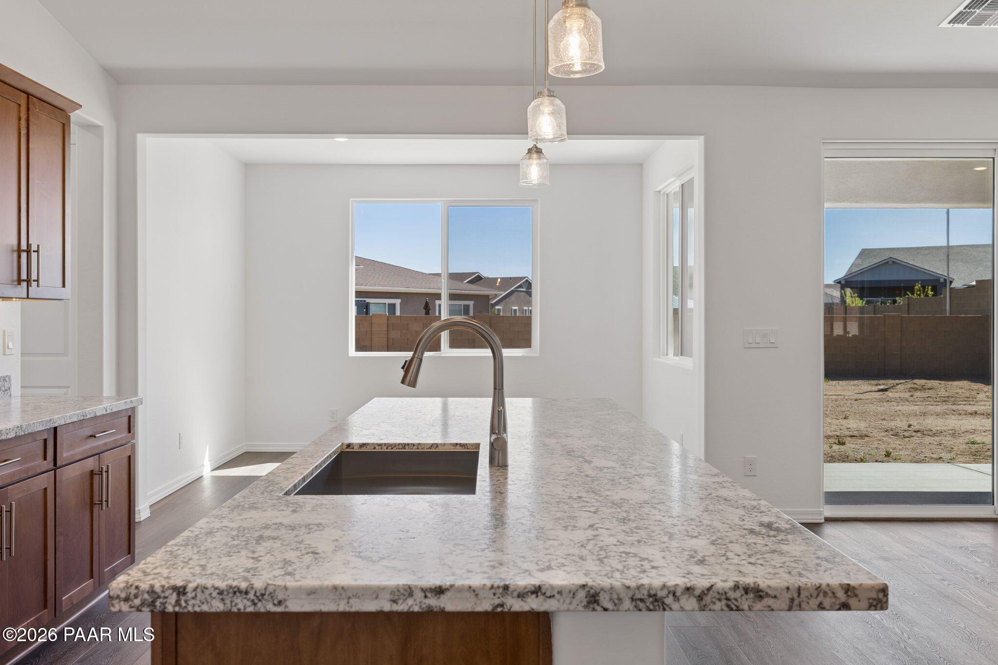 Modern kitchen island with granite countertop, stainless faucet, and pendant lights in Davidson Homes The Monarch A, Prescott, AZ