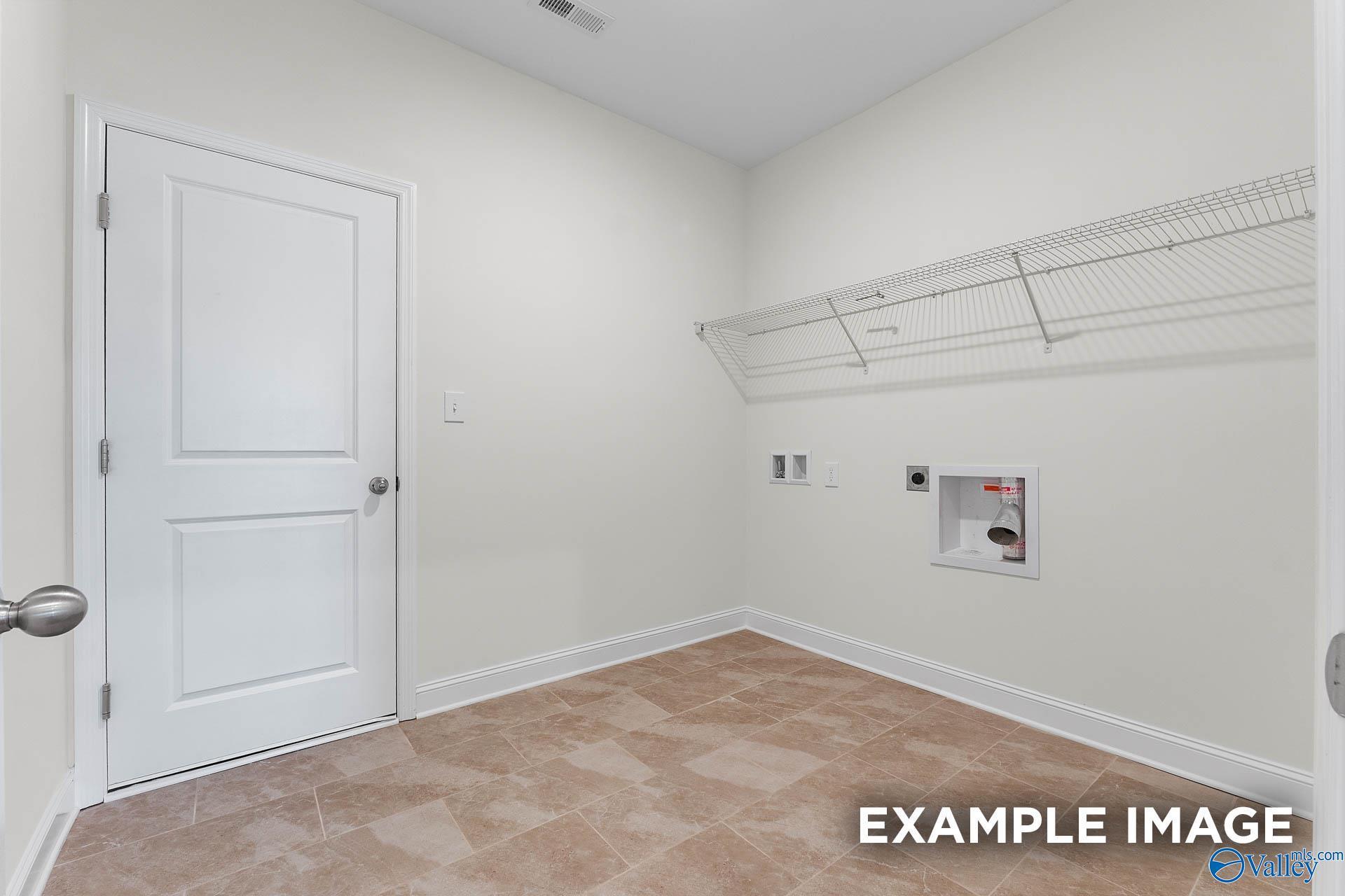 Functional laundry room with wire shelving, washer/dryer hookups, utility sink, and beige tile floor in The Emory 4-bedroom home, Toney, Alabama