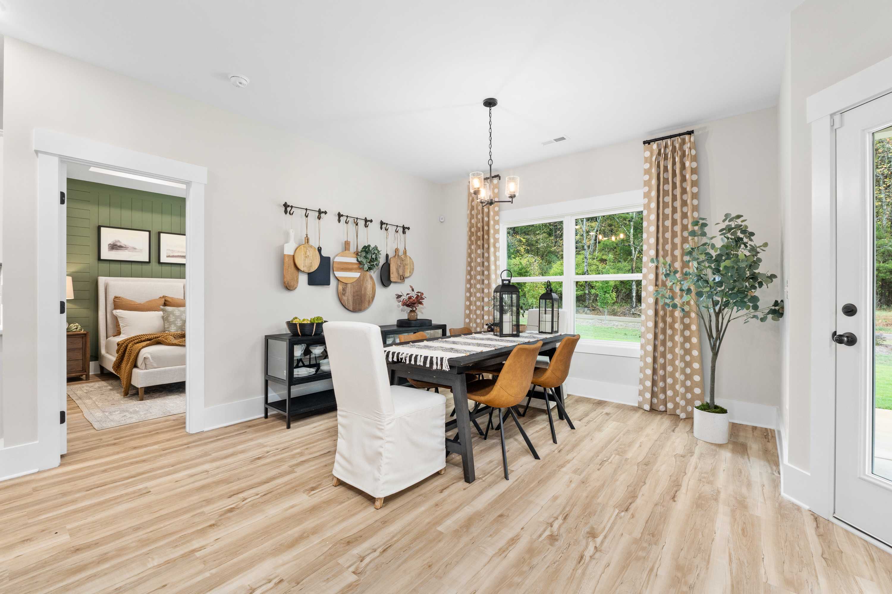Modern dining room in Spragins Cove Huntsville AL with farmhouse table, hardwood floors, hanging decor, and window garden view