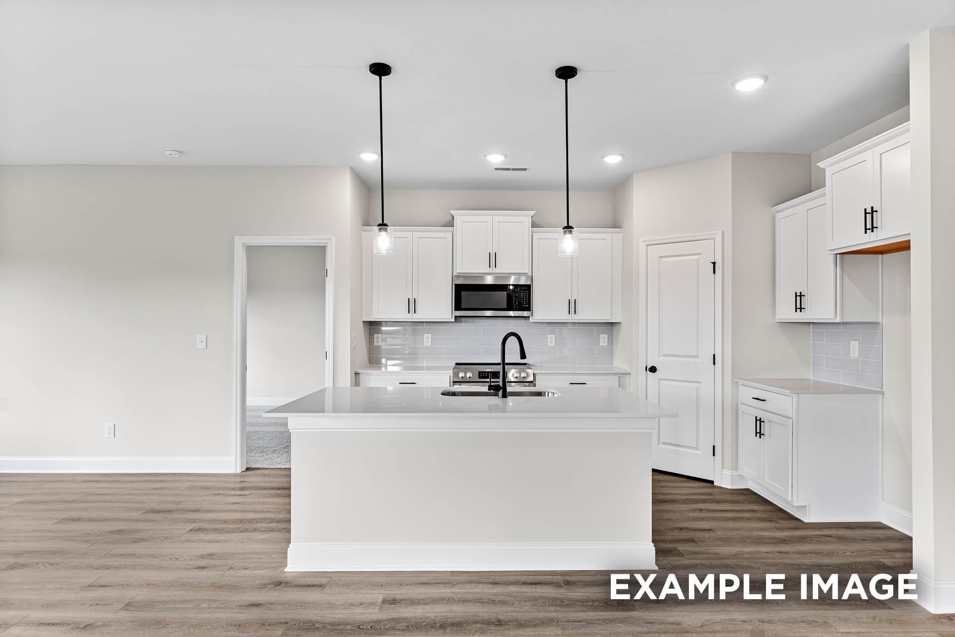 Modern kitchen with white cabinets, island, and pendant lighting in The Franklin E floor plan at Bailey Park, Fayetteville.