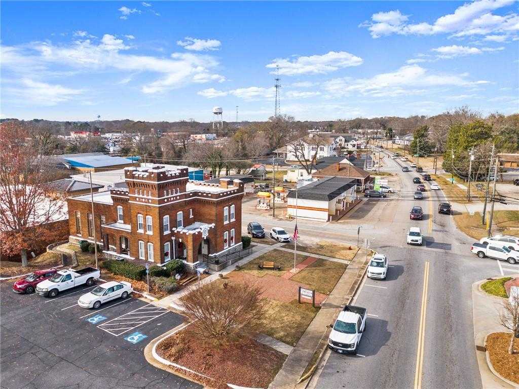Aerial view of historic red brick courthouse in downtown Winder, Georgia, with autumn foliage, water tower, and tree-lined streets